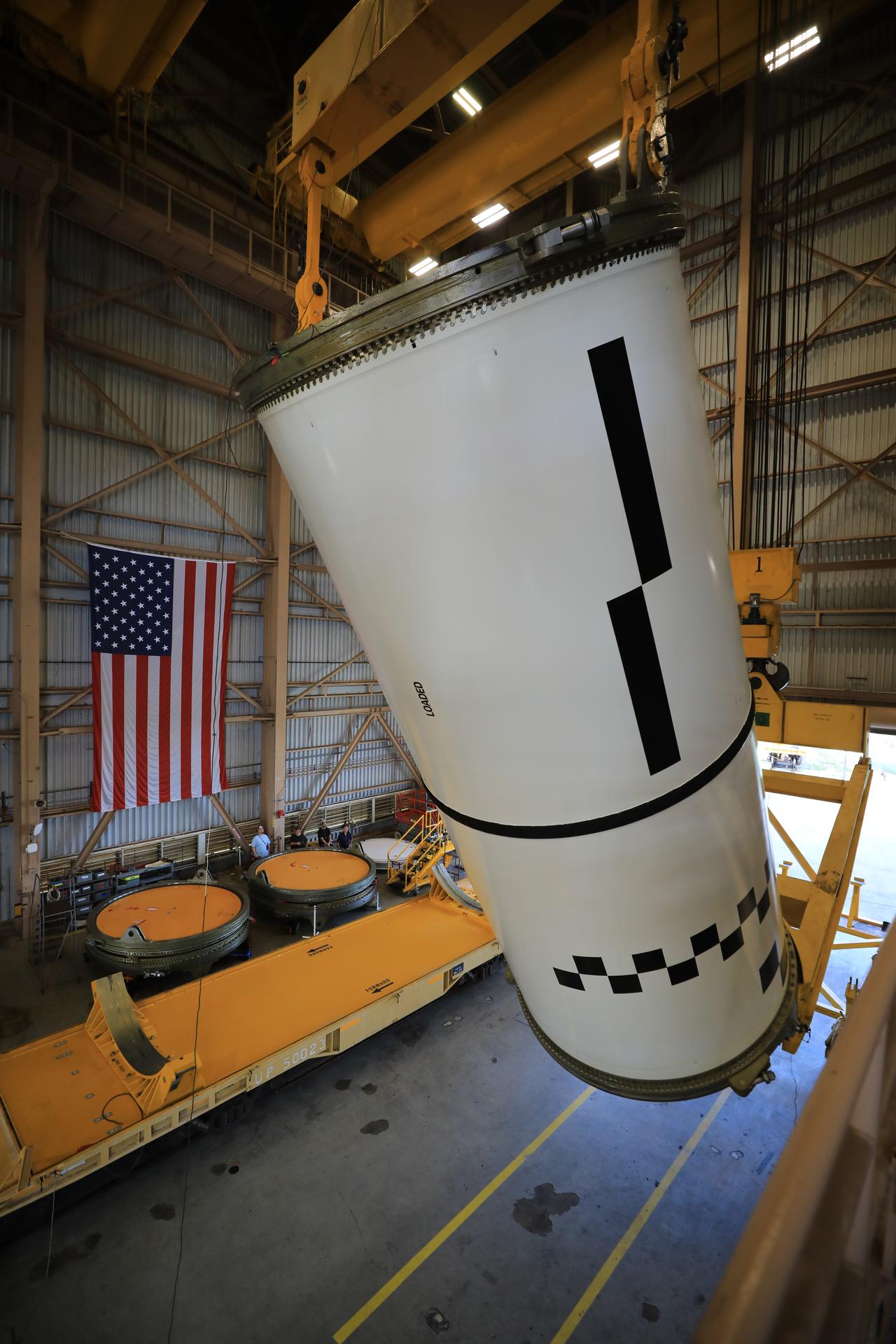 Technicians use a massive crane to rotate and lift the right-hand aft center assembly solid rocket booster segment for NASA’s Artemis III SLS (Space Launch System) rocket onto a work stand at the Rotation, Processing, and Surge Facility at the agency’s Kennedy Space Center in Florida on Wednesday, July 29, 2026. The twin boosters, comprising five segments each manufactured by Northrop Grumman in Utah, will provide more than 75 percent of the SLS rocket’s total thrust at launch. The Artemis III mission will launch crew in the Orion spacecraft on top of the SLS rocket to test rendezvous and docking capabilities between Orion and commercial spacecraft needed to land astronauts on the Moon.