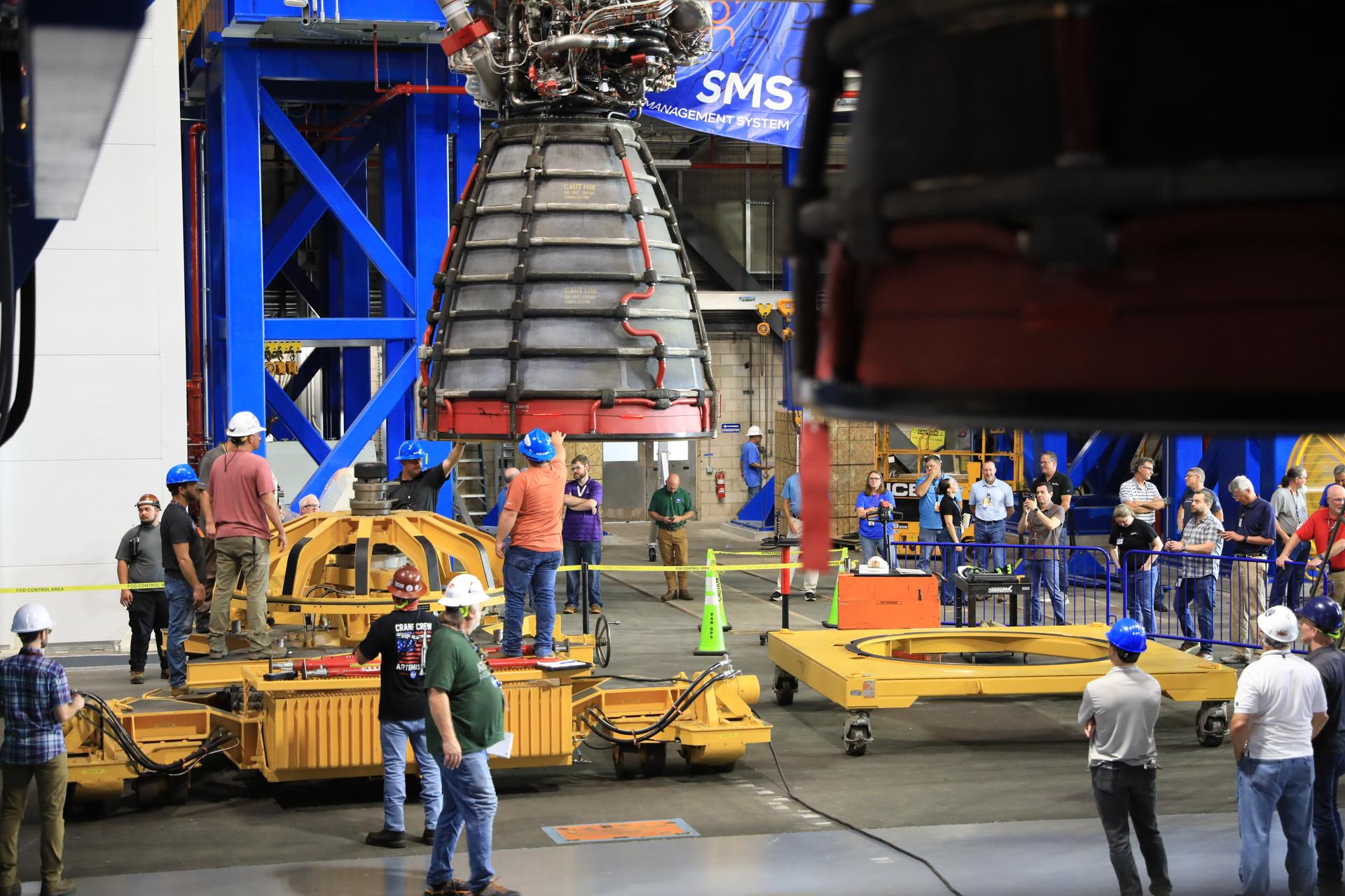 Technicians lift and transfer the #2 RS-25 SLS (Space Launch System) rocket engine (back) to the work stand. Visible in the foreground is the #3 engine already integrated with the Artemis III core stage rocket on Tuesday, Aug. 25, 2026, inside the Vehicle Assembly Building at NASA’s Kennedy Space Center in Florida. During Artemis III, the four RS‑25 engines will launch the Orion spacecraft and its crew of four into low Earth orbit, generating more than two million pounds of thrust at liftoff. 