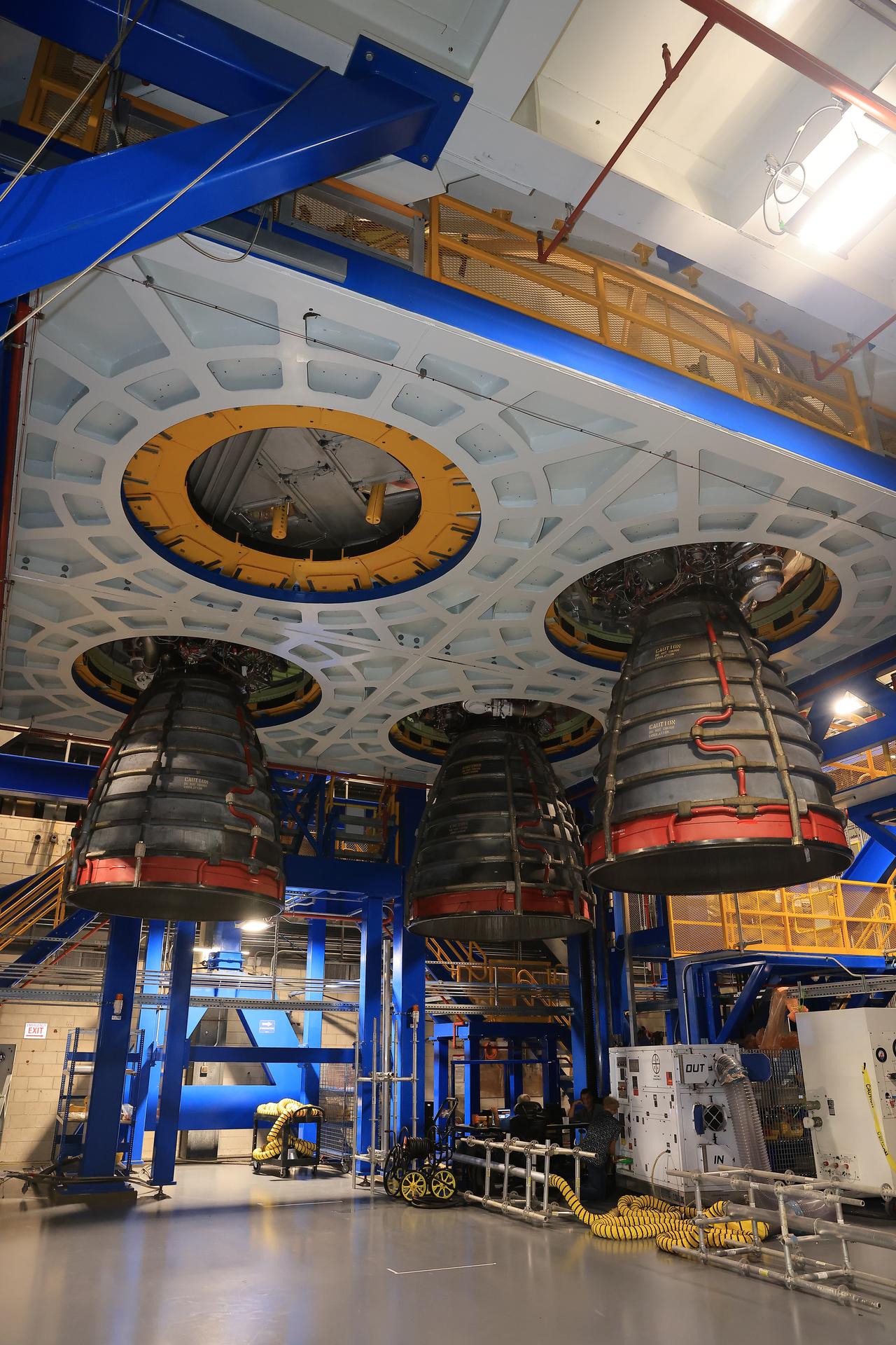 Technicians install three of four RS-25 SLS (Space Launch System) rocket engines on the work stand for integration with the Artemis III core stage rocket on Friday, Aug. 28, 2026, inside the Vehicle Assembly Building at NASA’s Kennedy Space Center in Florida. During Artemis III, the four RS-25 engines will launch the Orion spacecraft and its crew of four into low Earth orbit, generating more than two million pounds of thrust at liftoff.