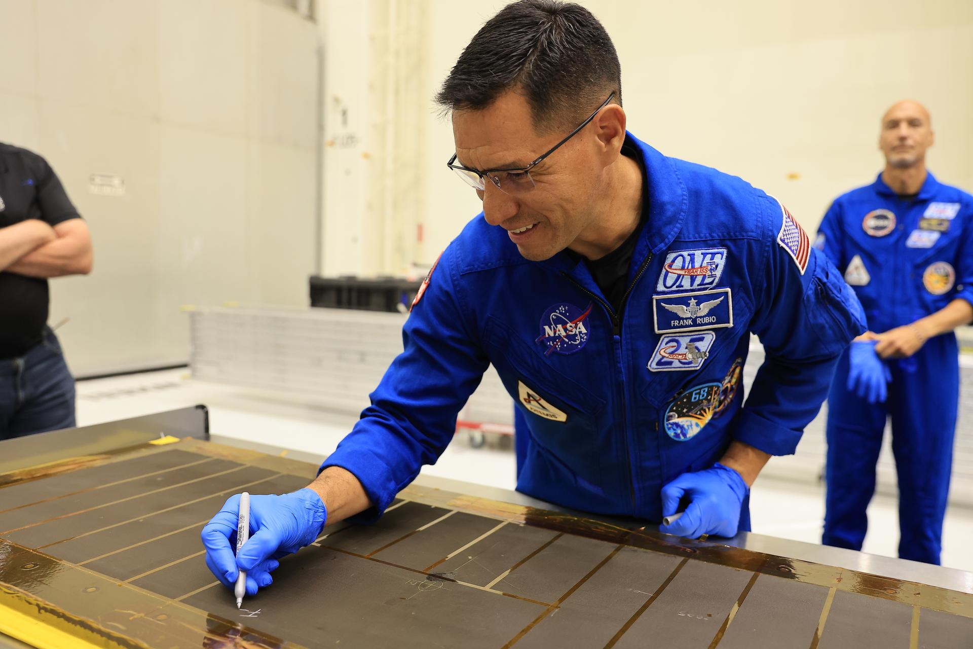 Artemis III NASA astronaut Frank Rubio, mission specialist, signs an interior center wall panel that will cover environmental control and life support system (ECLSS) components inside the Orion crew module in the Neil A. Armstrong Operations and Checkout Building at Kennedy Space Center in Florida on Wednesday, Sept. 2, 2026. The Artemis III primary and backup crew members, including Rubio; NASA astronaut Randy Bresnik, commander; ESA (European Space Agency) astronaut Luca Parmitano, pilot; NASA astronaut Andre Douglas, mission specialist; and NASA astronaut Bob Hines, backup crew member, visited Kennedy to view progress on Artemis III hardware, marking the first visit by the entire crew and backup crew to the Florida spaceport. On Orion, ECLSS will make the crew module a habitable, safe place for astronauts and is key to survival as they travel on deep space missions.