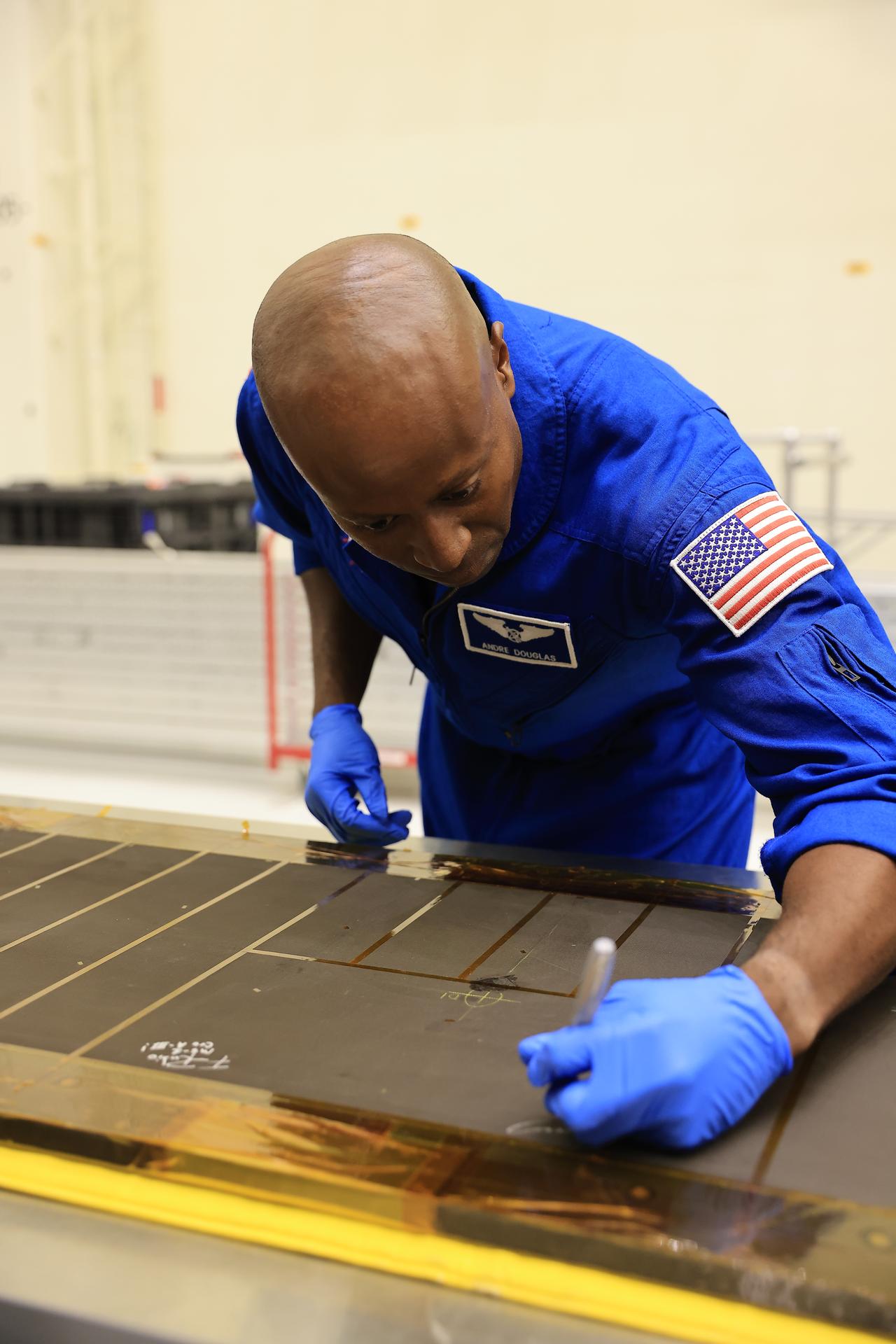 Artemis III NASA astronaut Andre Douglas, mission specialist, signs an interior center wall panel that will cover environmental control and life support system (ECLSS) components inside the Orion crew module in the Neil A. Armstrong Operations and Checkout Building at Kennedy Space Center in Florida on Wednesday, Sept. 2, 2026. The Artemis III primary and backup crew members, including Douglas; NASA astronaut Randy Bresnik, commander; ESA (European Space Agency) astronaut Luca Parmitano, pilot; NASA astronaut Frank Rubio, mission specialist; and NASA astronaut Bob Hines, backup crew member, visited Kennedy to view progress on Artemis III hardware, marking the first visit by the entire crew and backup crew to the Florida spaceport. On Orion, ECLSS will make the crew module a habitable, safe place for astronauts and is key to survival as they travel on deep space missions.