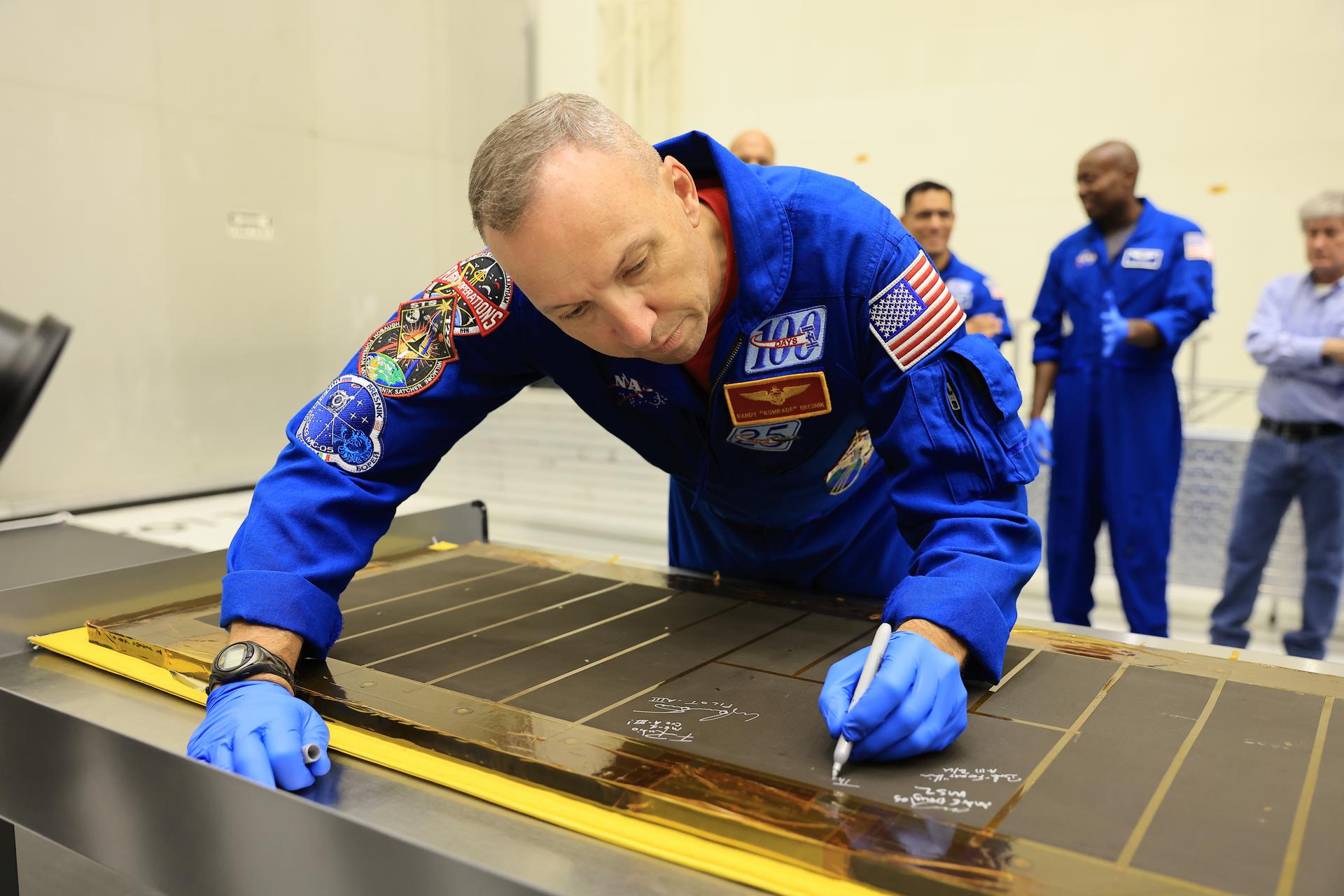 Artemis III NASA astronaut Randy Bresnik, commander, signs an interior center wall panel that will cover environmental control and life support system (ECLSS) components inside the Orion crew module in the Neil A. Armstrong Operations and Checkout Building at Kennedy Space Center in Florida on Wednesday, Sept. 2, 2026. The Artemis III primary and backup crew members, including Bresnik; ESA (European Space Agency) astronaut Luca Parmitano, pilot; NASA astronaut Andre Douglas, mission specialist; NASA astronaut Frank Rubio, mission specialist; and NASA astronaut Bob Hines, backup crew member, visited Kennedy to view progress on Artemis III hardware, marking the first visit by the entire crew and backup crew to the Florida spaceport. On Orion, ECLSS will make the crew module a habitable, safe place for astronauts and is key to survival as they travel on deep space missions.