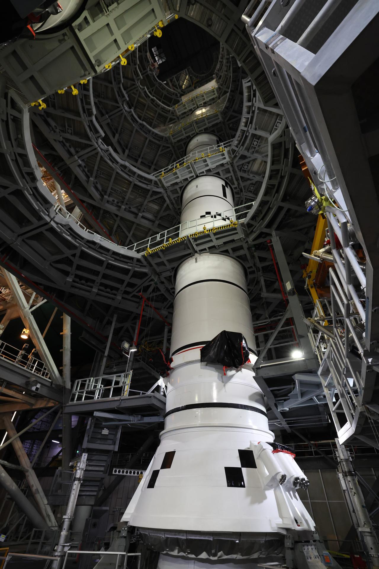In High Bay 3 of the Vehicle Assembly Building at NASA’s Kennedy Space Center in Florida, the right forward center booster for Artemis III is integrated onto the right booster segments on the mobile launcher for the SLS (Space Launch System) rocket on Friday, Sept. 11, 2026. The twin boosters, comprising of five segments each manufactured by Northrop Grumman in Utah, will provide more than 75 percent of the SLS rocket’s total thrust at launch. The Artemis III mission will launch crew in the Orion spacecraft on top of the SLS rocket to test rendezvous and docking capabilities between Orion and commercial spacecraft needed to land astronauts on the Moon. 