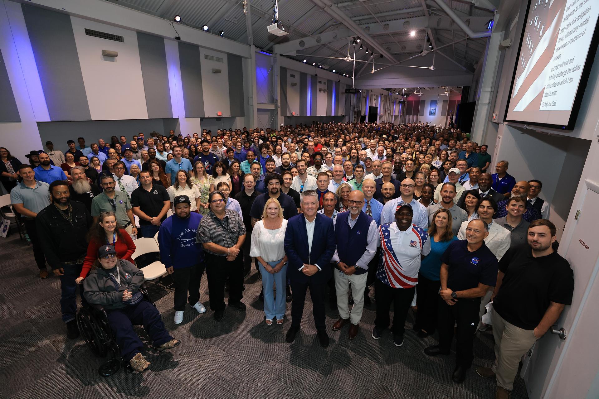 New NASA civil servants pose for a photograph with NASA’s Kennedy Space Center Director Brian Hughes (front, center) following their swearing-in ceremony on Monday, Sept. 21, 2026, inside the Astronauts Memorial Foundation’s Center for Space Education at the Kennedy Space Center Visitor Complex in Florida. The ceremony featured the swearing-in of employees formerly from the Consolidated Operations, Management, Engineering, and Test (COMET) contract, as well as outside hires, as part of the administrator’s workforce directive to restore technical core competencies within the civil servants ranks. 