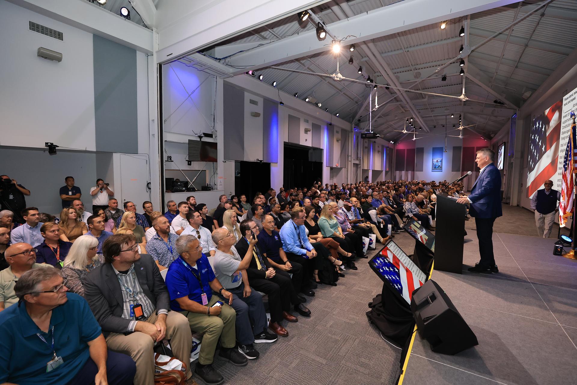 NASA’s Kennedy Space Center Director Brian Hughes (at podium) conducts a swearing-in ceremony for NASA’s latest civil servants on Monday, Sept. 21, 2026, inside the Astronauts Memorial Foundation’s Center for Space Education at the Kennedy Space Center Visitor Complex in Florida. The ceremony featured the swearing-in of employees formerly from the Consolidated Operations, Management, Engineering, and Test (COMET) contract, as well as outside hires, as part of the administrator’s workforce directive to restore technical core competencies within the civil servants ranks. 