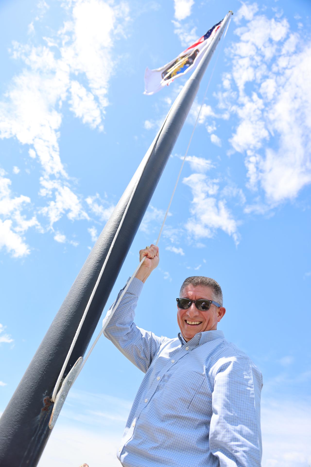 Richard Jones, deputy program manager, Commercial Crew Office, raises the agency’s SpaceX Crew-13 mission flag near the countdown clock at the NASA News Center at the agency’s Kennedy Space Center in Florida on Tuesday, Sept. 29, 2026. The Crew-13 mission will send NASA astronauts Jessica Watkins and Luke Delaney, CSA (Canadian Space Agency) astronaut Joshua Kutryk, and Roscosmos cosmonaut Sergey Teteryatnikov to the International Space Station aboard SpaceX’s Dragon spacecraft and Falcon 9 rocket at 11:10 a.m. EDT on Thursday, Oct. 1, from Cape Canaveral Space Force Station’s Space Launch Complex 40.