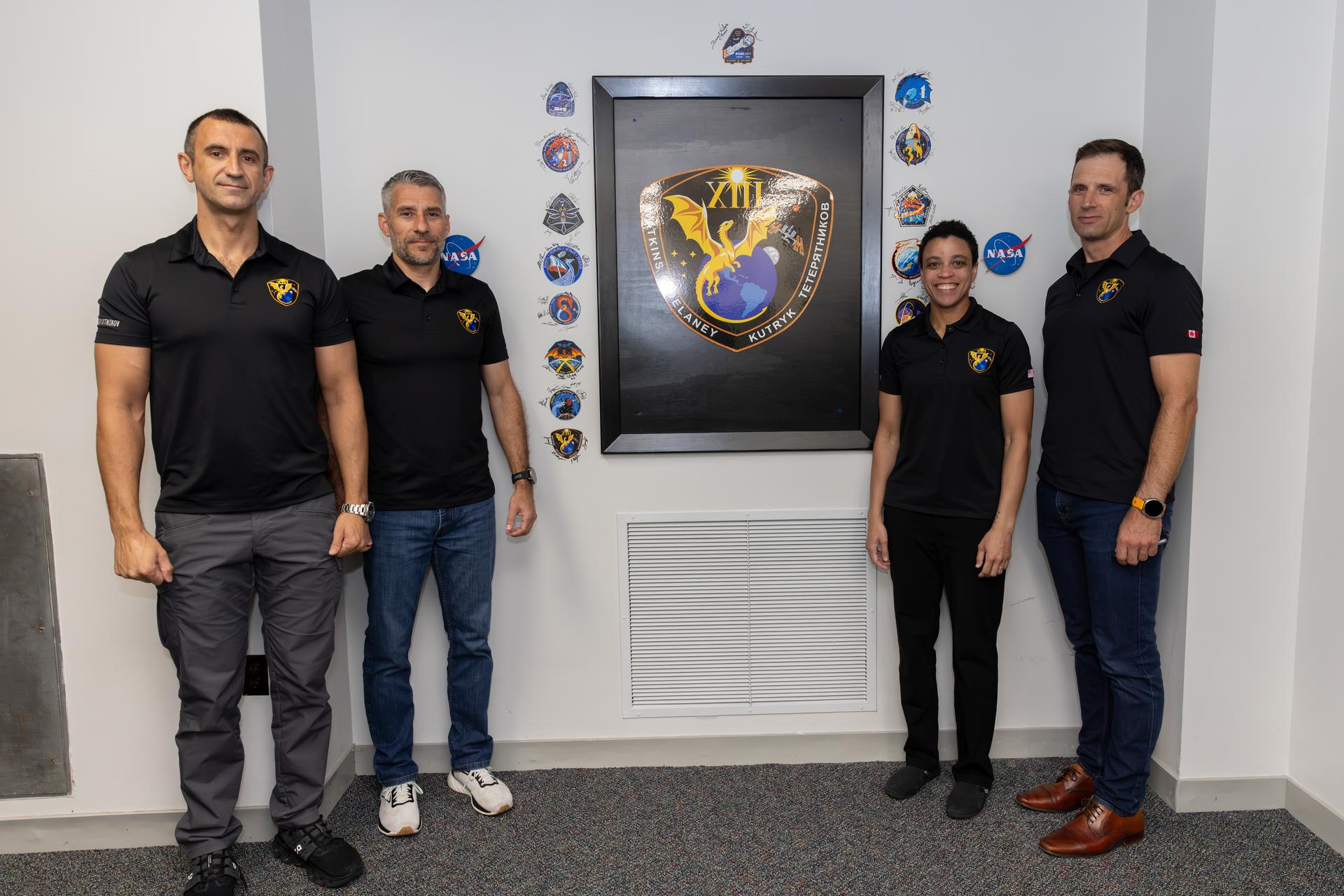 From right to left, CSA (Canadian Space Agency) astronaut Joshua Kutryk, NASA astronauts Jessica Watkins and Luke Delaney, and Roscosmos cosmonaut Sergey Teteryatnikov, pose next to their mission insignia inside the Astronaut Crew Quarters in the Neil A. Armstrong Operations and Checkout Building at NASA’s Kennedy Space Center in Florida on Tuesday, Sept. 29, 2026. NASA’s SpaceX Crew-13 crew members will launch aboard a SpaceX Dragon spacecraft and Falcon 9 to the International Space Station no earlier than 11:10 a.m. EDT on Thursday, Oct. 1, from Cape Canaveral Space Force Station’s Space Launch Complex 40.