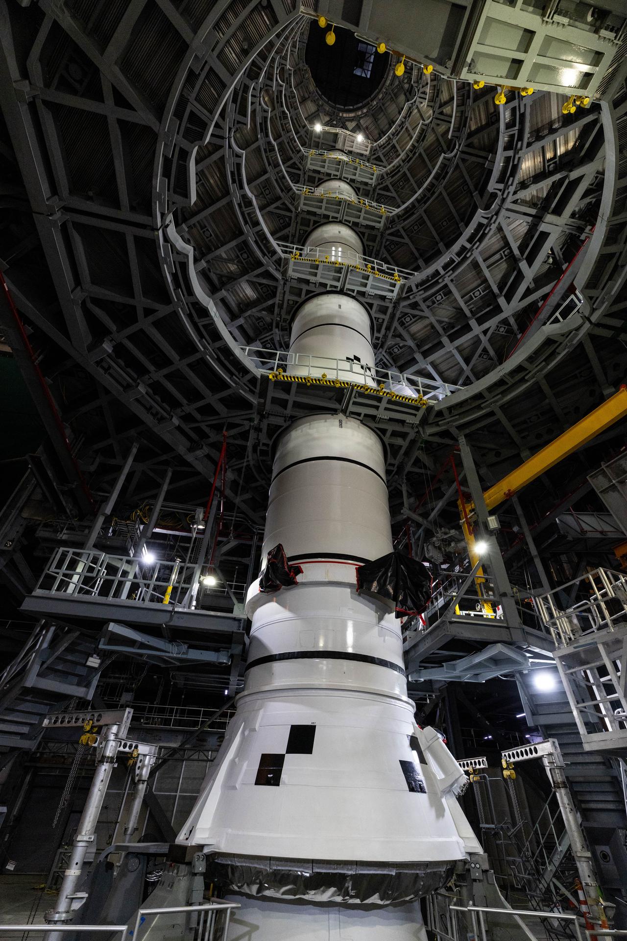Engineers with NASA’s Exploration Ground Systems integrate the aerodynamic nose cone onto the right forward motor segment on the twin SLS (Space Launch System) solid rocket boosters for Artemis III inside the Vehicle Assembly Building’s High Bay 3 at NASA’s Kennedy Space Center in Florida on Wednesday, Sept. 30, 2026. Each forward assembly contains an aerodynamic top, a forward skirt housing avionics, and frustum housing motors that allow the boosters to separate from the SLS core stage after launch. The twin solid boosters will help support the remaining rocket components and the Orion spacecraft during final assembly of the Artemis III rocket and provide more than 75 percent of the total SLS thrust during liftoff from NASA Kennedy’s Launch Pad 39B.