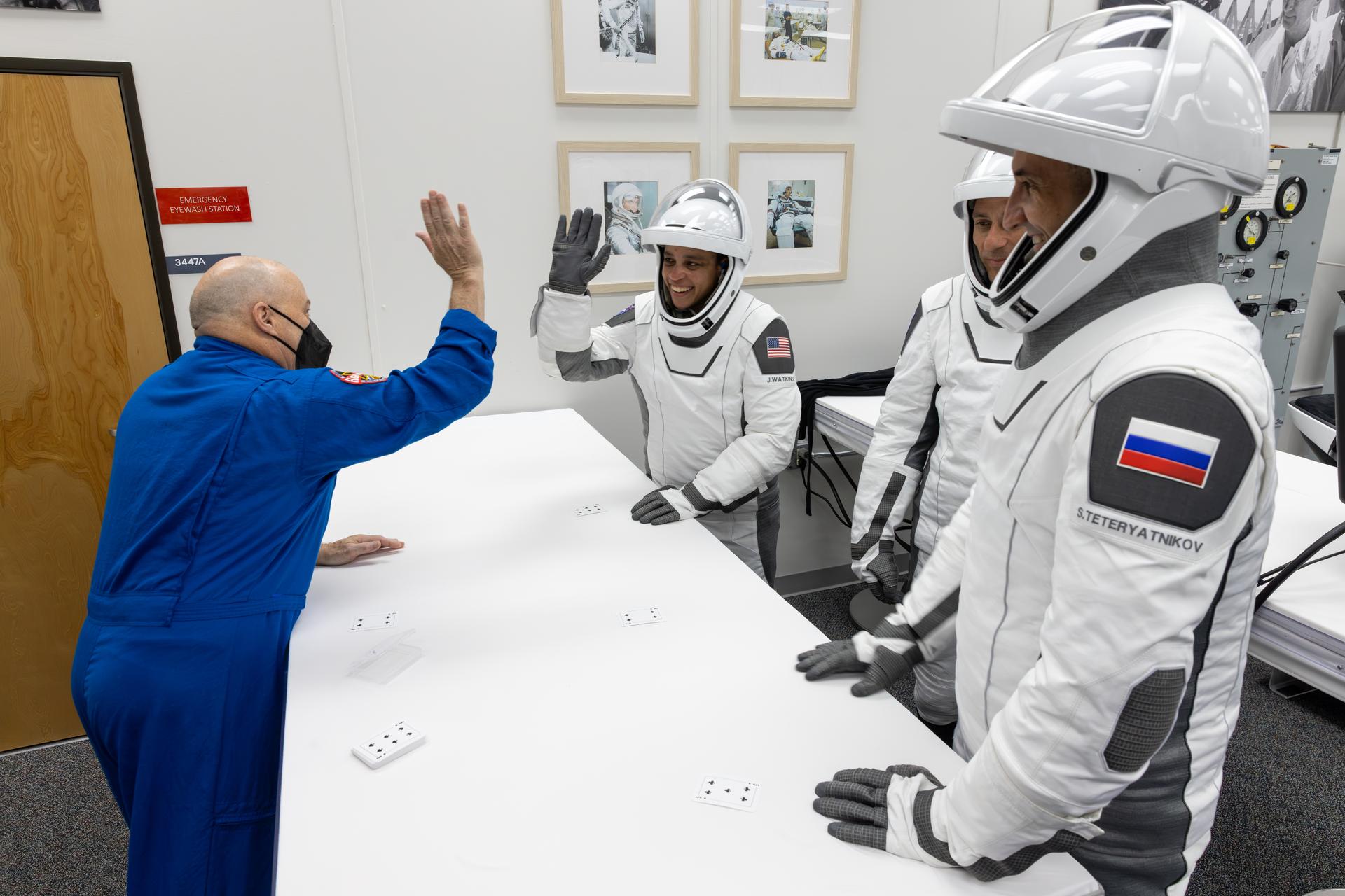 NASA astronaut chief Scott Tingle gives NASA astronaut Jessica Watkins a high-five during the traditional card game inside the Neil A. Armstrong Operations and Checkout Building at the agency’s Kennedy Space Center in Florida ahead of launch to the International Space Station on Thursday, Oct. 1, 2026. From left to right, Watkins, NASA astronaut Luke Delaney, along with Roscosmos cosmonaut Sergey Teteryatnikov are scheduled to lift off aboard SpaceX’s Dragon spacecraft and Falcon 9 rocket no earlier than 11:10 a.m. EDT, from Space Launch Complex 40 at Cape Canaveral Space Force Station in Florida.