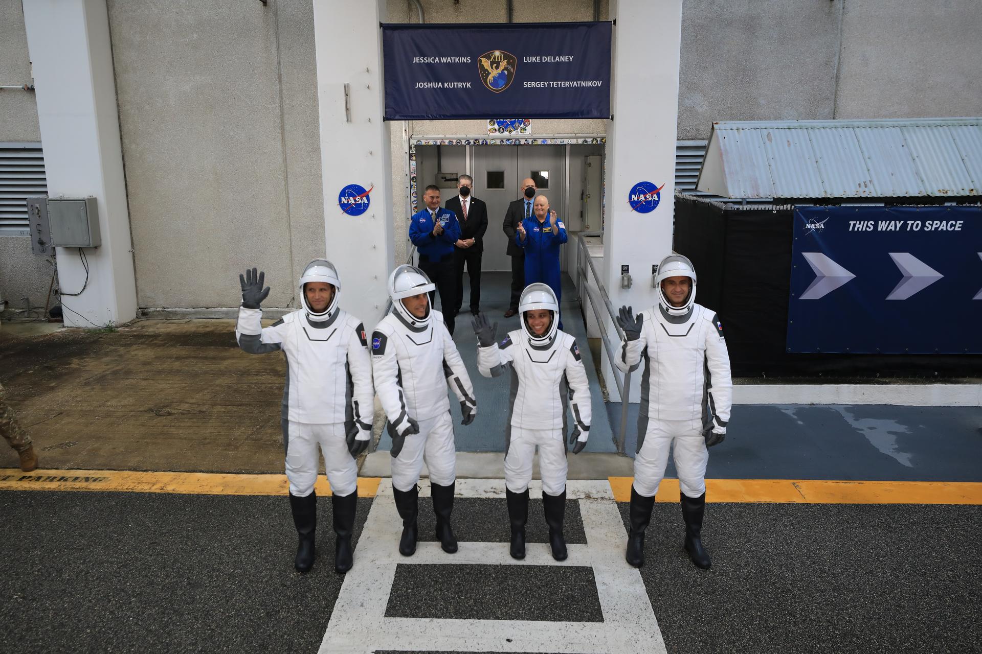 From left to right, NASA astronauts Luke Delaney and Jessica Watkins, along with Roscosmos cosmonaut Sergey Teteryatnikov, and CSA (Canadian Space Agency) astronaut Joshua Kutryk (back), wave to family and friends as they prepare to depart the Neil A. Armstrong Operations and Checkout Building at the agency’s Kennedy Space Center in Florida for nearby Space Launch Complex 40 at Cape Canaveral Space Force Station for launch of Crew-13 on Thursday, Oct. 1, 2026. Crew-13 is scheduled to lift off aboard SpaceX’s Dragon spacecraft and Falcon 9 rocket no earlier than 11:10 a.m. EDT, from Space Launch Complex 40 at Cape Canaveral Space Force Station in Florida.