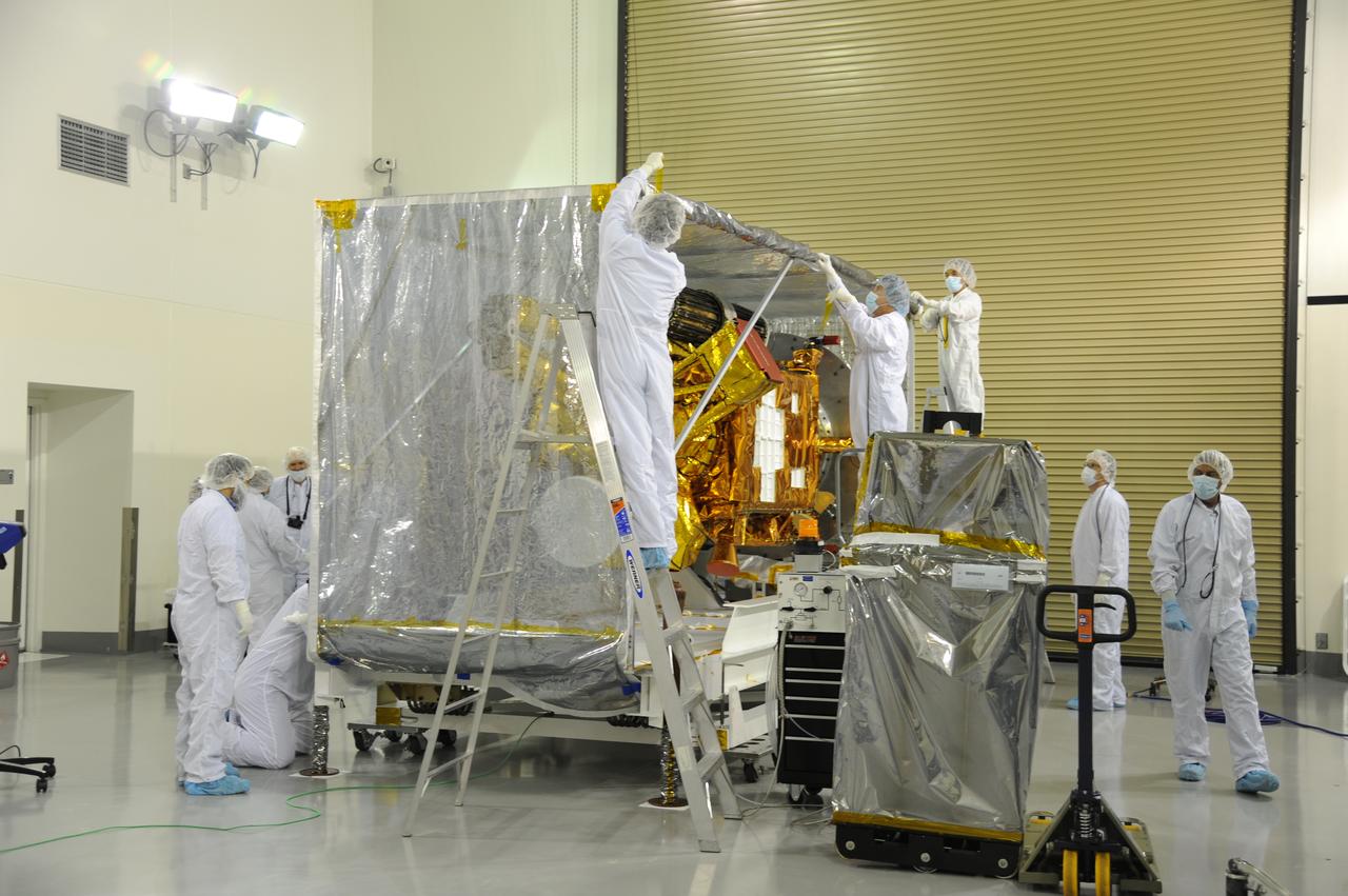 Workers remove the protective covering from around NASA's Soil Moisture Active Passive, or SMAP, spacecraft in the Astrotech payload processing facility on Vandenberg Air Force Base in California during a post-shipment inspection. The covering protected the spacecraft from static-charge buildup and contamination while it was in transit from NASA's Jet Propulsion Laboratory in Pasadena, California. SMAP will launch on a Delta II 7320 configuration vehicle featuring a United Launch Alliance first stage booster powered by an Aerojet Rocketdyne RS-27A main engine and three Alliant Techsystems, or ATK, strap-on solid rocket motors. Once on station in Earth orbit, SMAP will provide global measurements of soil moisture and its freeze/thaw state. These measurements will be used to enhance understanding of processes that link the water, energy and carbon cycles, and to extend the capabilities of weather and climate prediction models. SMAP data also will be used to quantify net carbon flux in boreal landscapes and to develop improved flood prediction and drought monitoring capabilities. Launch from Space Launch Complex 2 is targeted for Jan. 29, 2015. 