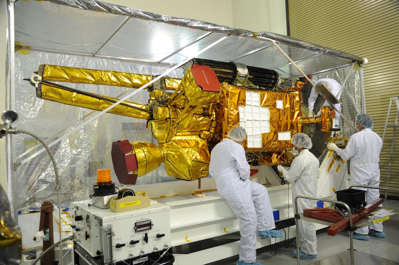Workers inspect NASA's Soil Moisture Active Passive, or SMAP, spacecraft after its protective covering is removed in the Astrotech payload processing facility on Vandenberg Air Force Base in California during a post-shipment inspection. The covering protected the spacecraft from static-charge buildup and contamination while it was in transit from NASA's Jet Propulsion Laboratory in Pasadena, California. SMAP will launch on a Delta II 7320 configuration vehicle featuring a United Launch Alliance first stage booster powered by an Aerojet Rocketdyne RS-27A main engine and three Alliant Techsystems, or ATK, strap-on solid rocket motors. Once on station in Earth orbit, SMAP will provide global measurements of soil moisture and its freeze/thaw state. These measurements will be used to enhance understanding of processes that link the water, energy and carbon cycles, and to extend the capabilities of weather and climate prediction models. SMAP data also will be used to quantify net carbon flux in boreal landscapes and to develop improved flood prediction and drought monitoring capabilities. Launch from Space Launch Complex 2 is targeted for Jan. 29, 2015.
