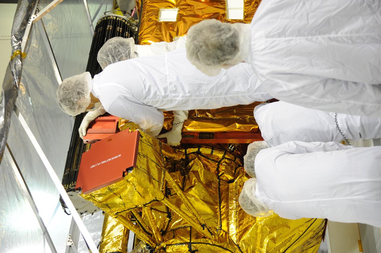 Workers inspect instrument and optics covers on NASA's Soil Moisture Active Passive, or SMAP, spacecraft in the Astrotech payload processing facility on Vandenberg Air Force Base in California during a post-shipment inspection. The spacecraft was delivered to the launch site today from NASA's Jet Propulsion Laboratory in Pasadena, California. SMAP will launch on a Delta II 7320 configuration vehicle featuring a United Launch Alliance first stage booster powered by an Aerojet Rocketdyne RS-27A main engine and three Alliant Techsystems, or ATK, strap-on solid rocket motors. Once on station in Earth orbit, SMAP will provide global measurements of soil moisture and its freeze/thaw state. These measurements will be used to enhance understanding of processes that link the water, energy and carbon cycles, and to extend the capabilities of weather and climate prediction models. SMAP data also will be used to quantify net carbon flux in boreal landscapes and to develop improved flood prediction and drought monitoring capabilities. Launch from Space Launch Complex 2 is targeted for Jan. 29, 2015.