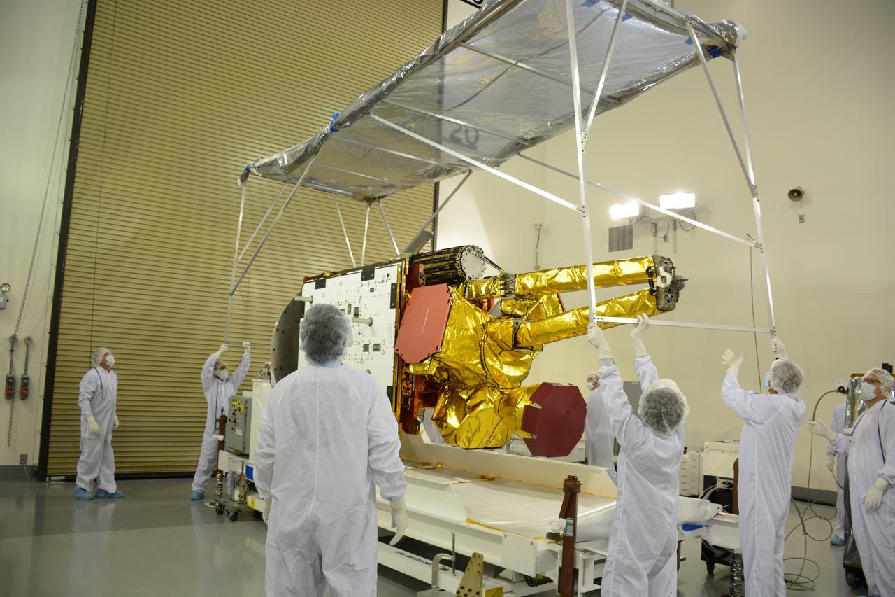 Inside the Astrotech payload processing facility on Vandenberg Air Force Base in California, engineers and technicians remove a protective covering from NASA's Soil Moisture Active Passive, or SMAP, spacecraft. SMAP will launch on a Delta II 7320 configuration vehicle featuring a United Launch Alliance first stage booster powered by an Aerojet Rocketdyne RS-27A main engine and three Alliant Techsystems, or ATK, strap-on solid rocket motors. Once on station in Earth orbit, SMAP will provide global measurements of soil moisture and its freeze/thaw state. These measurements will be used to enhance understanding of processes that link the water, energy and carbon cycles, and to extend the capabilities of weather and climate prediction models. SMAP data also will be used to quantify net carbon flux in boreal landscapes and to develop improved flood prediction and drought monitoring capabilities. Launch from Space Launch Complex 2 is targeted for Jan. 29, 2015.