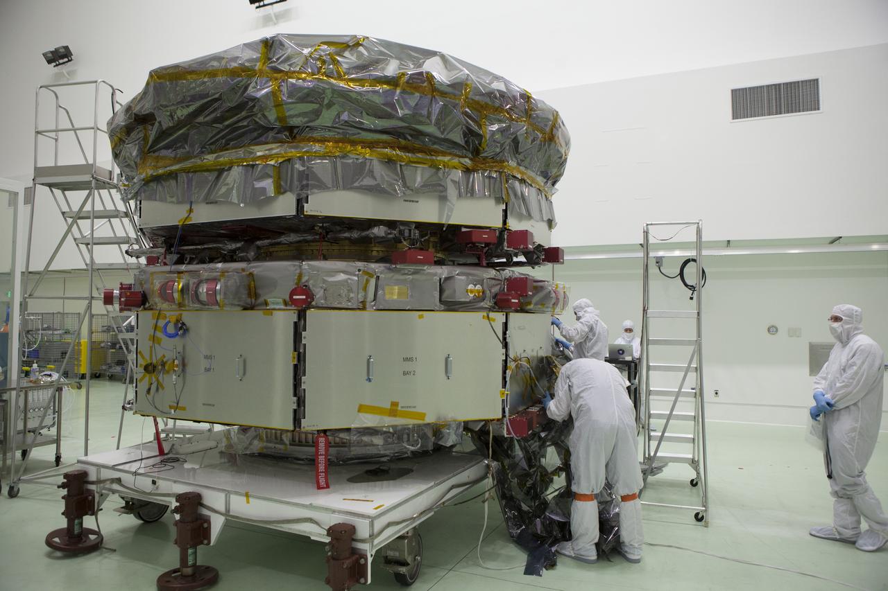 Technicians remove the protective covering from the lower stack, mini-stack number 1, two of the observatories for NASA's Magnetospheric Multiscale Observatory, or MMS, in Building 1 D high bay at the Astrotech payload processing facility in Titusville, Florida, near Kennedy Space Center. The MMS upper stack, mini-stack number 2, is scheduled to arrive in about two weeks. MMS is a Solar Terrestrial Probes mission comprising four identically instrumented spacecraft that will use Earth’s magnetosphere as a laboratory to study the microphysics of three fundamental plasma processes: magnetic reconnection, energetic particle acceleration and turbulence. Launch aboard a United Launch Alliance Atlas V rocket from Space Launch Complex 41 on Cape Canaveral Air Force Station is targeted for March 12, 2015.