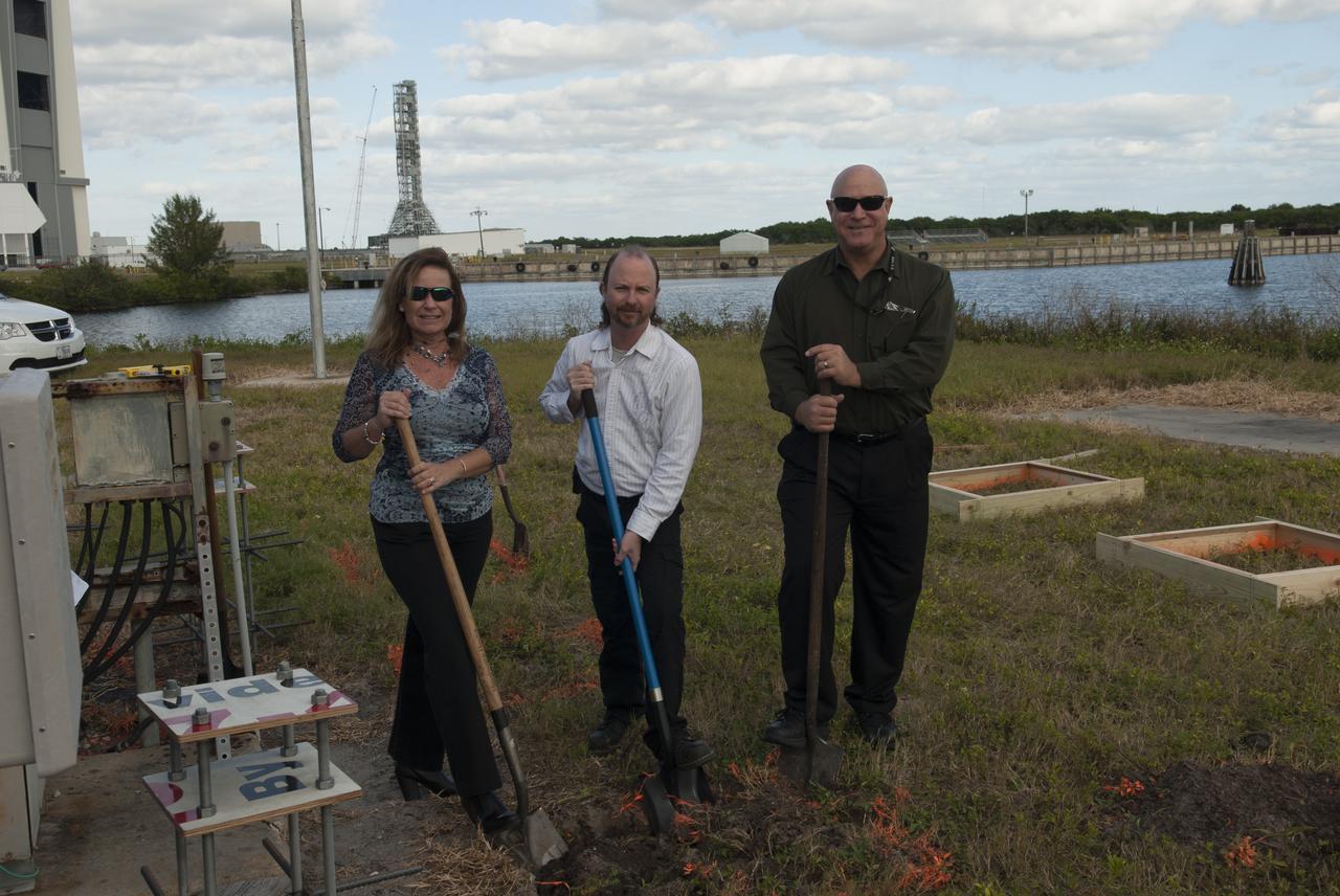At NASA's Kennedy Space Center in Florida, Project Manager Sonja Hernandez, Kennedy TV senior systems engineer Ronald Gonser and Kennedy/IMCS senior manager Jeff Van Pelt dig in behind the current countdown clock during the groundbreaking ceremony for the new countdown clock. The old timepiece was designed by Kennedy engineers and built by Kennedy technicians in 1969. Not including the triangular concrete and aluminum base, the famous landmark is nearly 6 feet 70 inches high, 26 feet 315 inches wide and 3 feet deep. The new display will be similar in size, with the screen being nearly 26 feet wide by 7 feet high.
