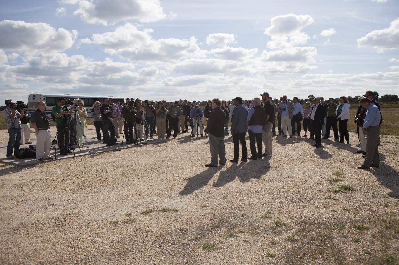 Bob Richards, standing at left in front of the cameras, co-founder and chief executive officer of Moon Express Inc., of Moffett Field, California, speaks to the media during an event to announce the company's selection to utilize Kennedy Space Center facilities as part of NASA's Lunar Cargo Transportation and Landing by Soft Touchdown, or Lunar CATALYST, initiative. Third from left in the group is former NASA Apollo astronaut Buzz Aldrin. The event took place at Kennedy's automated landing and hazard avoidance technology, or ALHAT, hazard field at the north end of the Shuttle Landing Facility. Moon Express is developing a lander with capabilities that will enable delivery of payloads to the surface of the moon, as well as new science and exploration missions of interest to NASA and scientific and academic communities. Moon Express will base its activities at Kennedy and utilize the Morpheus ALHAT field and a hangar nearby for CATALYST testing. The Advanced Exploration Systems Division of NASA's Human Exploration and Operations Mission Directorate manages Lunar CATALYST.