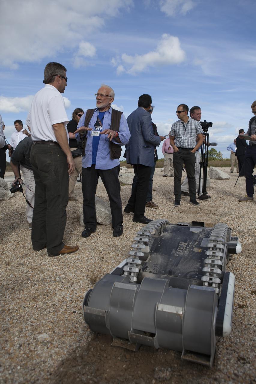 Rob Mueller, left, NASA senior technologist in the Surface Systems Office in Kennedy Space Center's Engineering and Technology Directorate, talks with former NASA Apollo astronaut Buzz Aldrin during a demonstration of the Regolith Advanced Surface System Operations Robot, or RASSOR, at the automated landing and hazard avoidance technology, or ALHAT, hazard field at the north end of the Shuttle Landing Facility at NASA's Kennedy Space Center in Florida. The event was held to announce Moon Express Inc., of Moffett Field, California is selected to utilize Kennedy facilities for NASA's Lunar Cargo Transportation and Landing by Soft Touchdown, or Lunar CATALYST, initiative. Moon Express is developing a lander with capabilities that will enable delivery of payloads to the surface of the moon, as well as new science and exploration missions of interest to NASA and scientific and academic communities. Moon Express will base its activities at Kennedy and utilize the Morpheus ALHAT field and a hangar nearby for CATALYST testing. The Advanced Exploration Systems Division of NASA's Human Exploration and Operations Mission Directorate manages Lunar CATALYST.