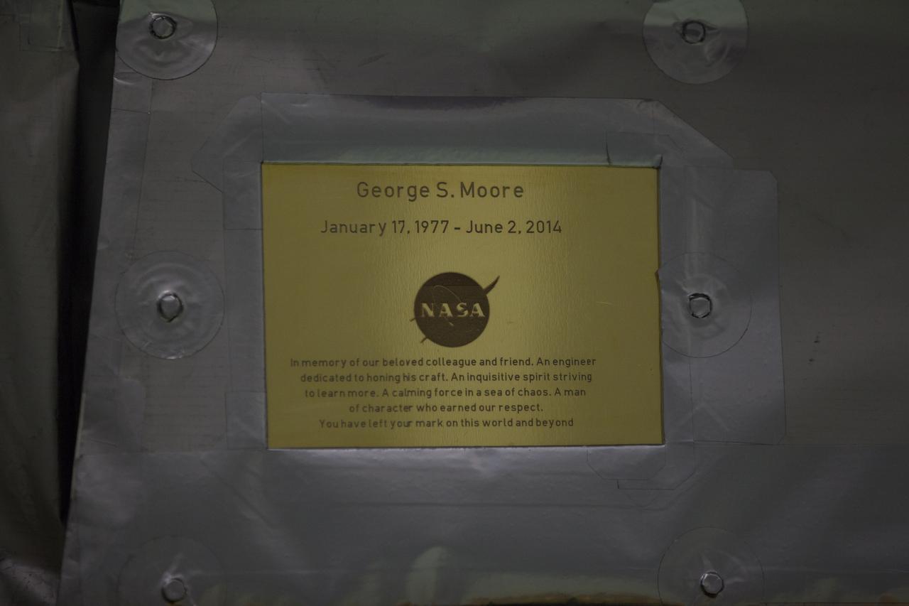 A plaque affixed to the side of a Magnetospheric Multiscale, or MMS, observatory dedicates the mission to George S. Moore, now deceased, an engineer who was a beloved colleague and friend to the MMS team. MMS, led by a team from NASA's Goddard Space Flight Center, is a Solar Terrestrial Probes mission consisting of four identically instrumented spacecraft that will use Earth’s magnetosphere as a laboratory to study the microphysics of three fundamental plasma processes: magnetic reconnection, energetic particle acceleration and turbulence. Launch aboard a United Launch Alliance Atlas V rocket from Space Launch Complex 41 on Cape Canaveral Air Force Station is targeted for March 12, 2015.