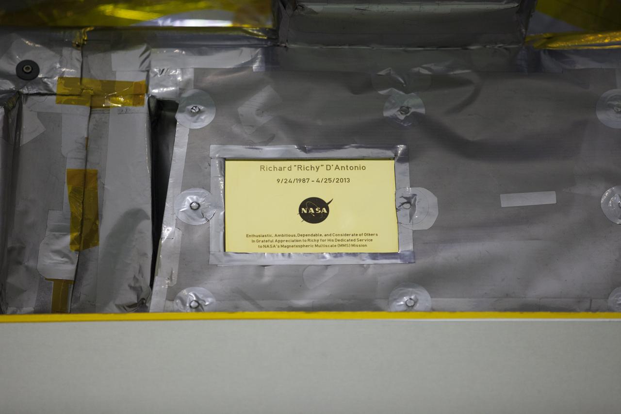 A plaque affixed to the side of a Magnetospheric Multiscale, or MMS, observatory dedicates the mission to Richard “Richy” D’Antonio, now deceased, in grateful appreciation for his dedicated service to NASA’s MMS mission. MMS, led by a team from NASA's Goddard Space Flight Center, is a Solar Terrestrial Probes mission consisting of four identically instrumented spacecraft that will use Earth’s magnetosphere as a laboratory to study the microphysics of three fundamental plasma processes: magnetic reconnection, energetic particle acceleration and turbulence. Launch aboard a United Launch Alliance Atlas V rocket from Space Launch Complex 41 on Cape Canaveral Air Force Station is targeted for March 12, 2015.