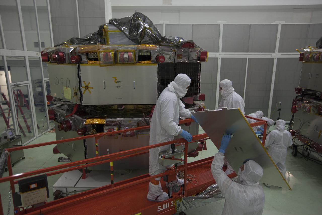 Workers inspect the solar arrays on the Magnetospheric Multiscale, or MMS, observatories in the Building 1 D high bay of the Astrotech payload processing facility in Titusville, Florida, near Kennedy Space Center. The two MMS spacecraft comprising the upper deck arrived Nov. 12; the two comprising the lower stack arrived Oct. 29. MMS, led by a team from NASA's Goddard Space Flight Center, is a Solar Terrestrial Probes mission consisting of four identically instrumented spacecraft that will use Earth’s magnetosphere as a laboratory to study the microphysics of three fundamental plasma processes: magnetic reconnection, energetic particle acceleration and turbulence. Launch aboard a United Launch Alliance Atlas V rocket from Space Launch Complex 41 on Cape Canaveral Air Force Station is targeted for March 12, 2015.
