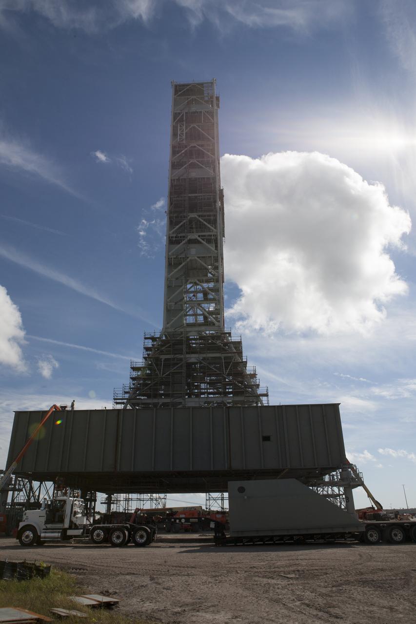 Modifications continue on the Mobile Launcher, or ML, at the Mobile Launcher Park Site at NASA’s Kennedy Space Center in Florida. The haunch, a structure that will support the launch vehicle on the ML, arrives by flatbed truck at the park site. The ML is being modified and strengthened to accommodate the weight, size and thrust at launch of NASA's Space Launch System, or SLS, and Orion spacecraft. In 2013, the agency awarded a contract to J.P. Donovan Construction Inc. of Rockledge, Fla., to modify the ML, which is one of the key elements of ground support equipment that is being upgraded by the Ground Systems Development and Operations Program at Kennedy. The existing 24-foot exhaust hole is being enlarged and strengthened for the larger, heavier SLS rocket. The ML will carry the SLS rocket and Orion spacecraft to Launch Pad 39B for its first uncrewed mission, Exploration Mission-1, in 2018.