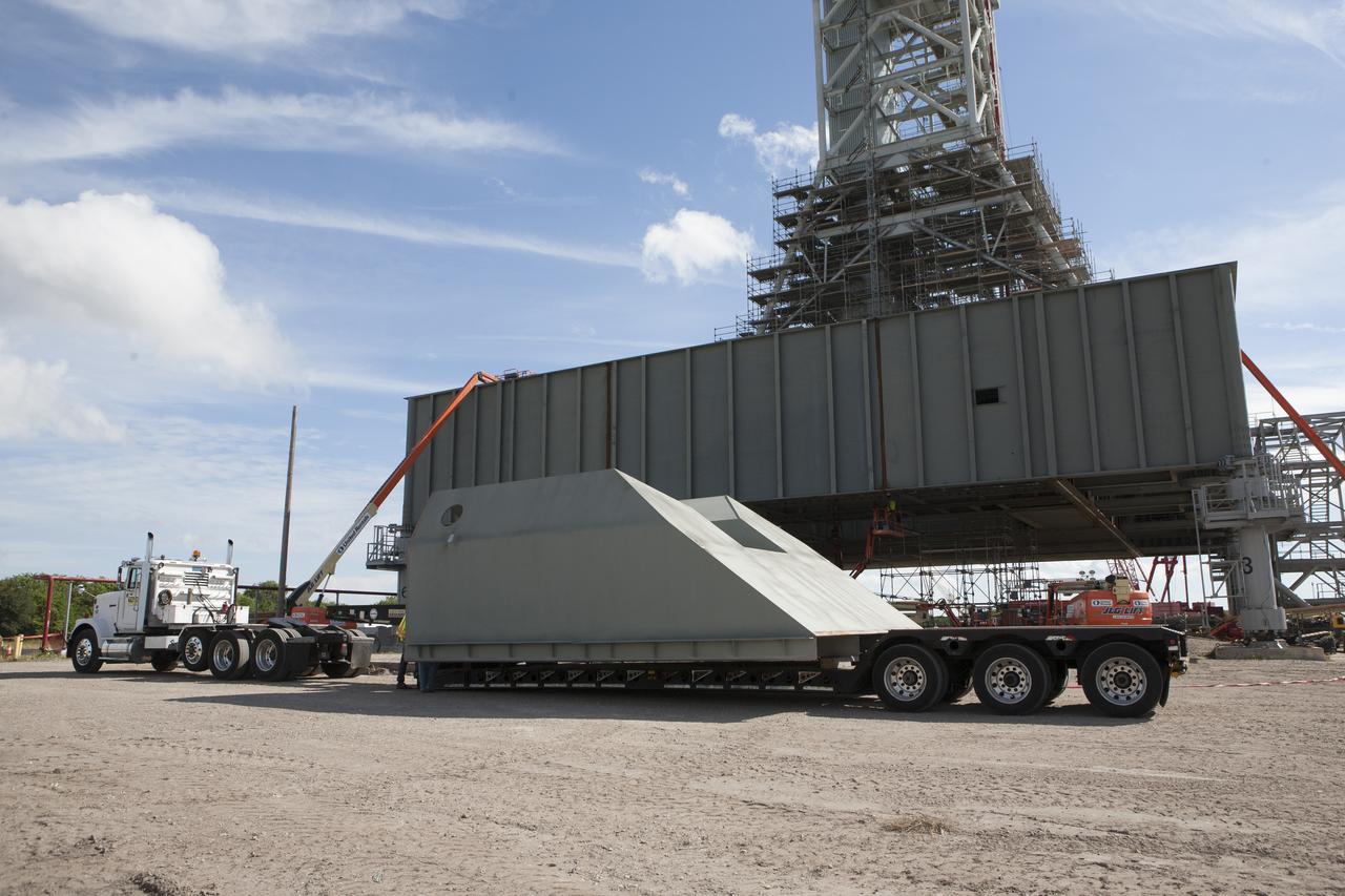 Modifications continue on the Mobile Launcher, or ML, at the Mobile Launcher Park Site at NASA’s Kennedy Space Center in Florida. The haunch, a structure that will support the launch vehicle on the ML, arrives by flatbed truck at the park site. The ML is being modified and strengthened to accommodate the weight, size and thrust at launch of NASA's Space Launch System, or SLS, and Orion spacecraft. In 2013, the agency awarded a contract to J.P. Donovan Construction Inc. of Rockledge, Fla., to modify the ML, which is one of the key elements of ground support equipment that is being upgraded by the Ground Systems Development and Operations Program at Kennedy. The existing 24-foot exhaust hole is being enlarged and strengthened for the larger, heavier SLS rocket. The ML will carry the SLS rocket and Orion spacecraft to Launch Pad 39B for its first uncrewed mission, Exploration Mission-1, in 2018.