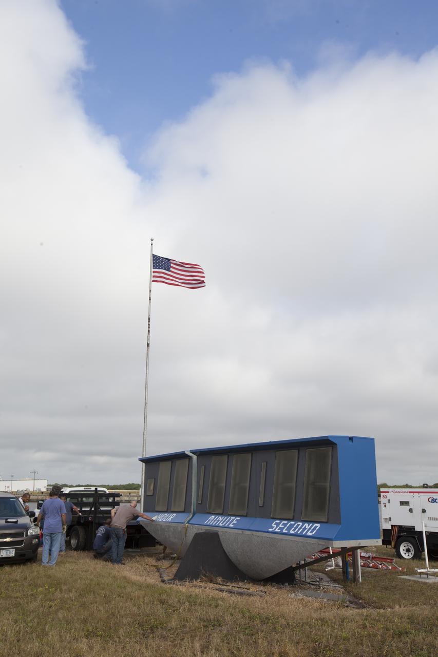 At NASA's Kennedy Space Center in Florida, the historic countdown clock at the spaceport's Press Site is disassembled for removal. Kennedy has requested to acquire the countdown clock from the agency’s Artifact Working Group at NASA Headquarters for likely display at the Kennedy Space Center Visitor Complex. A new modern multimedia display soon will be installed, similar to the screens seen at sporting venues, is in the works. The new screen will be nearly 26 feet wide by 7 feet high. The old timepiece was designed by Kennedy engineers and built by Kennedy technicians in 1969. Not including the triangular concrete and aluminum base, the famous landmark is nearly six feet high, 26 feet wide and 3 feet deep. The new display will be similar in size, with the screen being nearly 26 feet wide by seven feet high.