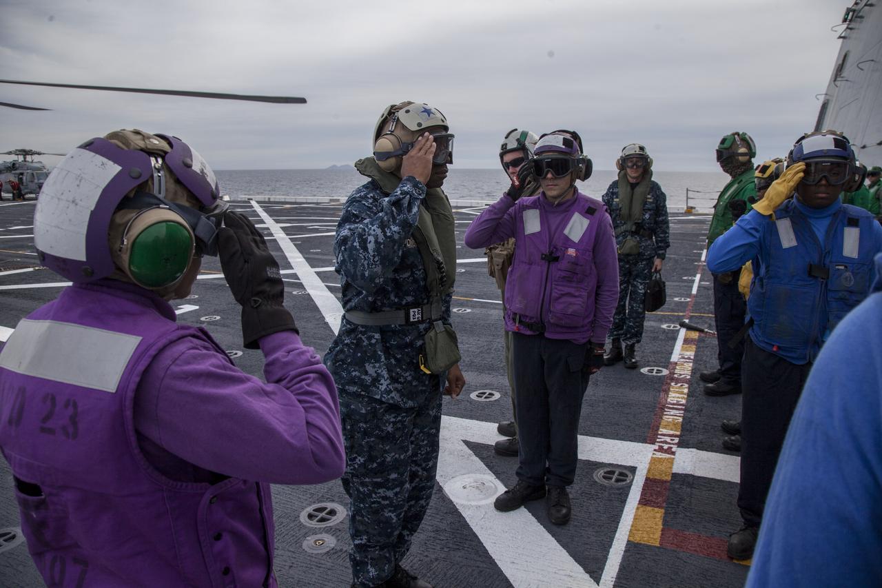 U.S. Navy and Helicopter Sea Combat Squadron 8 salute Rear Admiral Fernandez L. "Frank" Ponds, Commander, Expeditionary Strike Group 3 during his visit on the deck of the USS Anchorage near Naval Base San Diego in California. The ship is heading out to sea in the Pacific Ocean. NASA and the U.S. Navy are making preparations ahead of Orion's flight test for recovery of the crew module, forward bay cover and parachutes on its return from space and splashdown in the Pacific Ocean. The Ground Systems Development and Operations Program is leading the recovery efforts.