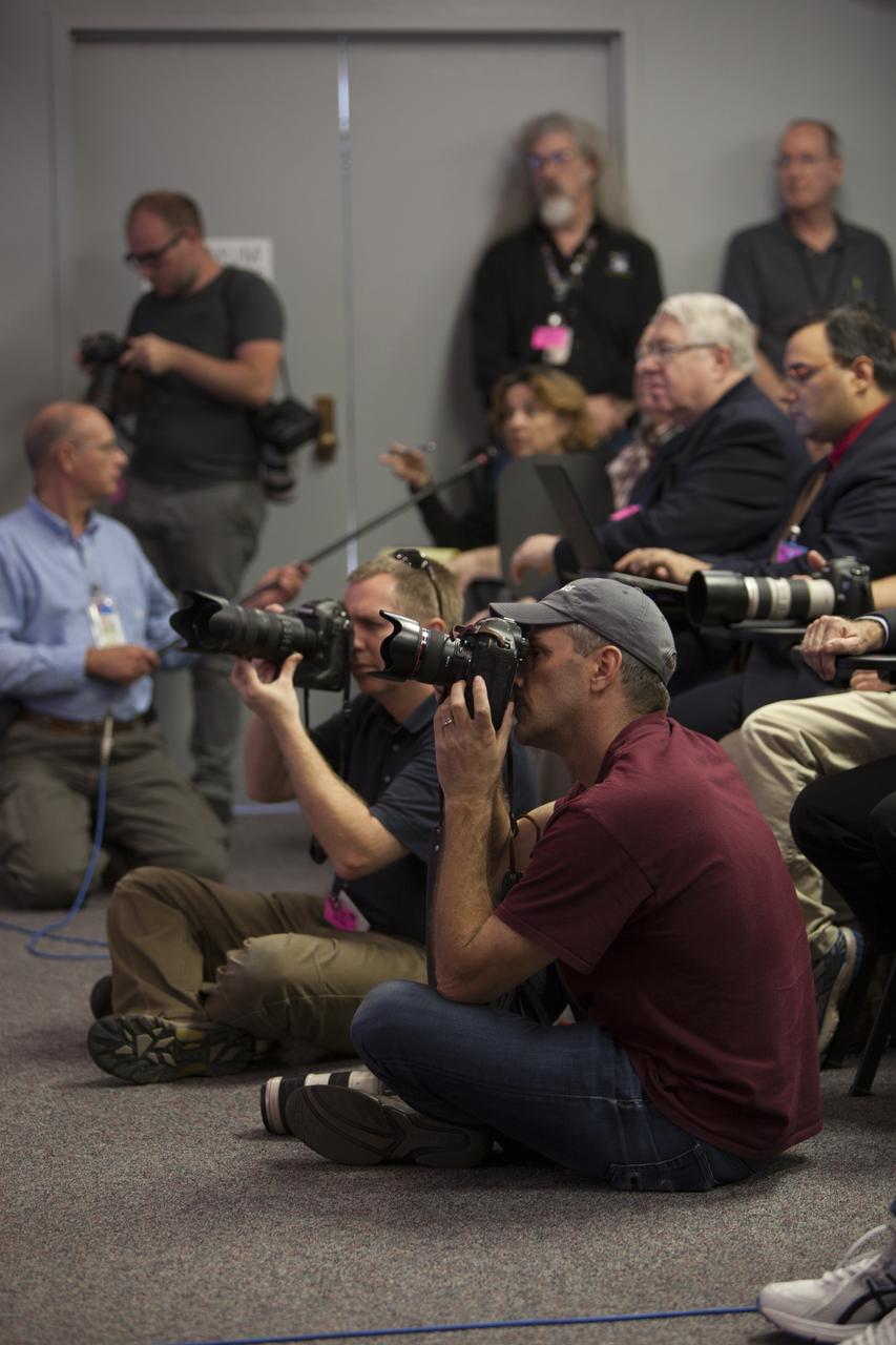 In the Kennedy Space Center’s Press Site auditorium, news media representatives listen and take photographs as NASA and industry leaders talk about the postponement of the Orion Flight Test launch due to an issue related to fill and drain valves on the Delta IV Heavy rocket.