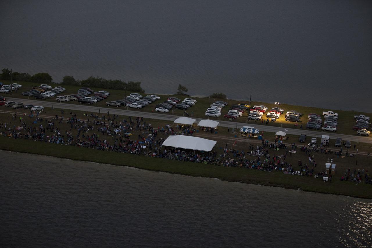 This helicopter view of the NASA Causeway connecting NASA's Kennedy Space Center with Cape Canaveral Air Force Staton shows the thousands of vehicles parked where guests gather to see the launch of the Orion Flight Test.