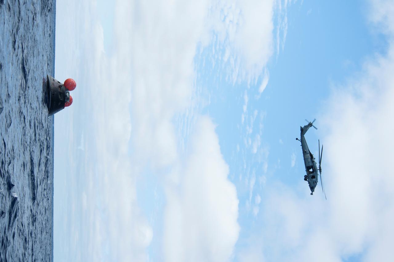 NASA's Orion spacecraft floats in the Pacific Ocean after splashdown from its first flight test in Earth orbit. An H60-S Seahawk helicopter hovers above to communicate the spacecraft's location back to the USS Anchorage. NASA, the U.S. Navy and Lockheed Martin are coordinating efforts to recover Orion and secure the spacecraft in the well deck of the USS Anchorage. Orion completed a two-orbit, four-and-a-half hour mission, to test systems critical to crew safety, including the launch abort system, the heat shield and the parachute system. The Ground Systems Development and Operations Program is leading the recovery efforts.