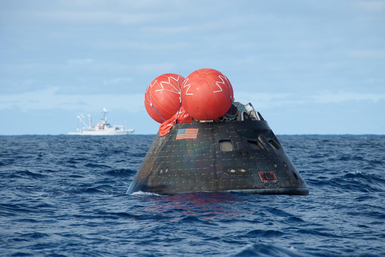 NASA's Orion spacecraft floats in the Pacific Ocean after splashdown from its first flight test in Earth orbit. In the background is the USNS Salvor. This U.S. Navy salvage ship was there as a backup in case it was needed. NASA, the U.S. Navy and Lockheed Martin are coordinating efforts to recover Orion and secure the spacecraft in the well deck of the USS Anchorage. Orion completed a two-orbit, four-and-a-half hour mission, to test systems critical to crew safety, including the launch abort system, the heat shield and the parachute system. The Ground Systems Development and Operations Program is leading the recovery efforts. 