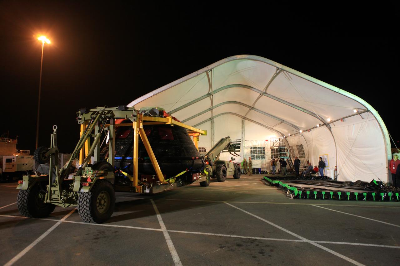 The Orion crew module is being moved into a covered structure at the Mole Pier at Naval Base San Diego in California where it will be prepared for return to NASA's Kennedy Space Center in Florida. Orion was secured on its crew module recovery cradle in the well deck of the USS Anchorage after it was recovered from the Pacific Ocean. After lifting off at 7:05 a.m. EST on Dec. 5, atop a Delta IV Heavy rocket from Space Launch Complex 37 at Cape Canaveral Air Force Station in Florida, Orion completed a two-orbit, four-and-a-half hour mission to test systems critical to crew safety, including the launch abort system, the heat shield and the parachute system. NASA, the U.S. Navy and Lockheed Martin coordinated efforts to recover Orion after splashdown in the Pacific Ocean. The Ground Systems Development and Operations Program led the recovery efforts. 