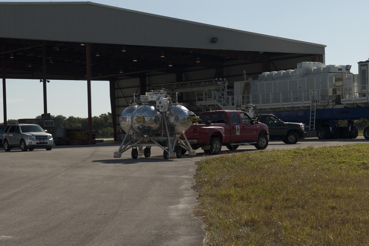NASA's Project Morpheus prototype lander is prepared for transport to the north end of the Shuttle Landing Facility for free flight test number 15 at NASA’s Kennedy Space Center in Florida. The lander will take off from the ground over a flame trench and use its autonomous landing and hazard avoidance technology, or ALHAT sensors, to survey the hazard field to determine safe landing sites. Project Morpheus tests NASA’s ALHAT and an engine that runs on liquid oxygen and methane, which are green propellants. These new capabilities could be used in future efforts to deliver cargo to planetary surfaces. Project Morpheus is being managed under the Advanced Exploration Systems, or AES, Division in NASA’s Human Exploration and Operations Mission Directorate. 