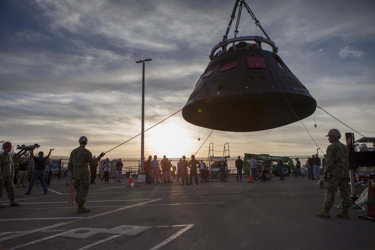 The Orion crew module is being moved by crane from its crew module recovery cradle and will be placed in the crew module transportation fixture at the Mole Pier at Naval Base San Diego in California. The fixture has been secured on the back of a flatbed truck. Orion is being prepared for the overland trip back to NASA's Kennedy Space Center in Florida. Orion was recovered from the Pacific Ocean after completing a two-orbit, four-and-a-half hour mission Dec. 5 to test systems critical to crew safety, including the launch abort system, the heat shield and the parachute system. NASA, the U.S. Navy and Lockheed Martin coordinated efforts to recover Orion. The Ground Systems Development and Operations Program led the recovery, offload and pre-transportation efforts. 