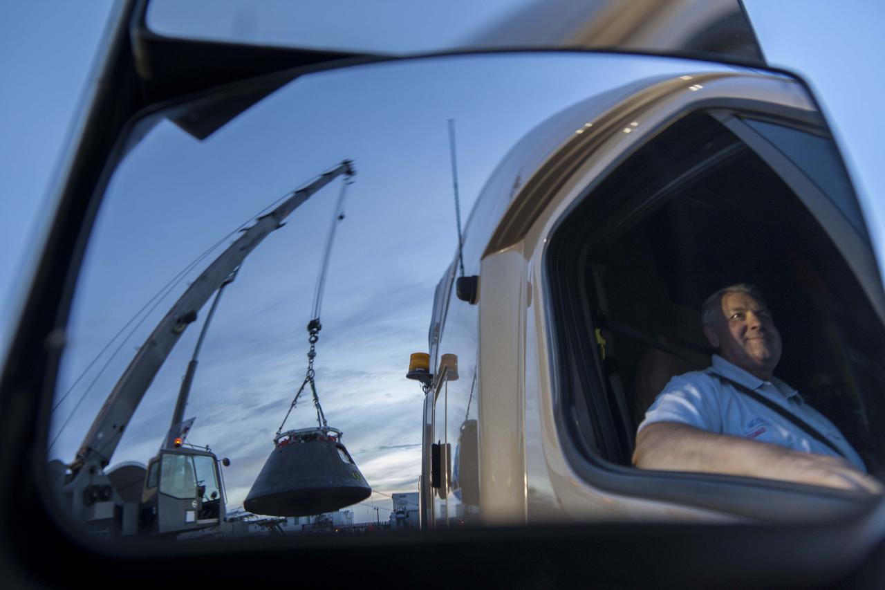 In this reflected view, the Orion crew module is being moved by crane from its crew module recovery cradle and will be placed in the crew module transportation fixture at the Mole Pier at Naval Base San Diego in California. The fixture has been secured on the back of a flatbed truck. Orion is being prepared for the overland trip back to NASA's Kennedy Space Center in Florida. Orion was recovered from the Pacific Ocean after completing a two-orbit, four-and-a-half hour mission Dec. 5 to test systems critical to crew safety, including the launch abort system, the heat shield and the parachute system. NASA, the U.S. Navy and Lockheed Martin coordinated efforts to recover Orion. The Ground Systems Development and Operations Program led the recovery, offload and pre-transportation efforts. 