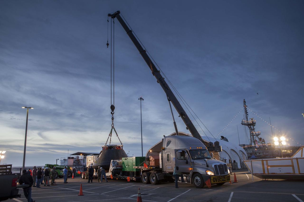 The Orion crew module is being lowered onto the crew module transportation fixture at the Mole Pier at Naval Base San Diego in California. The fixture has been secured on the back of a flatbed truck. Orion is being prepared for the overland trip back to NASA's Kennedy Space Center in Florida. Orion was recovered from the Pacific Ocean after completing a two-orbit, four-and-a-half hour mission Dec. 5 to test systems critical to crew safety, including the launch abort system, the heat shield and the parachute system. NASA, the U.S. Navy and Lockheed Martin coordinated efforts to recover Orion. The Ground Systems Development and Operations Program led the recovery, offload and pre-transportation efforts.