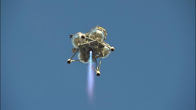 NASA’s Project Morpheus prototype lander soars overhead during free flight test No. 15 at the north end of the Shuttle Landing Facility at Kennedy Space Center in Florida. During the 97-second test, onboard autonomous landing and hazard avoidance technology sensors, or ALHAT, surveyed the hazard field for safe landing sites, then guided the lander forward and downward to a successful landing.