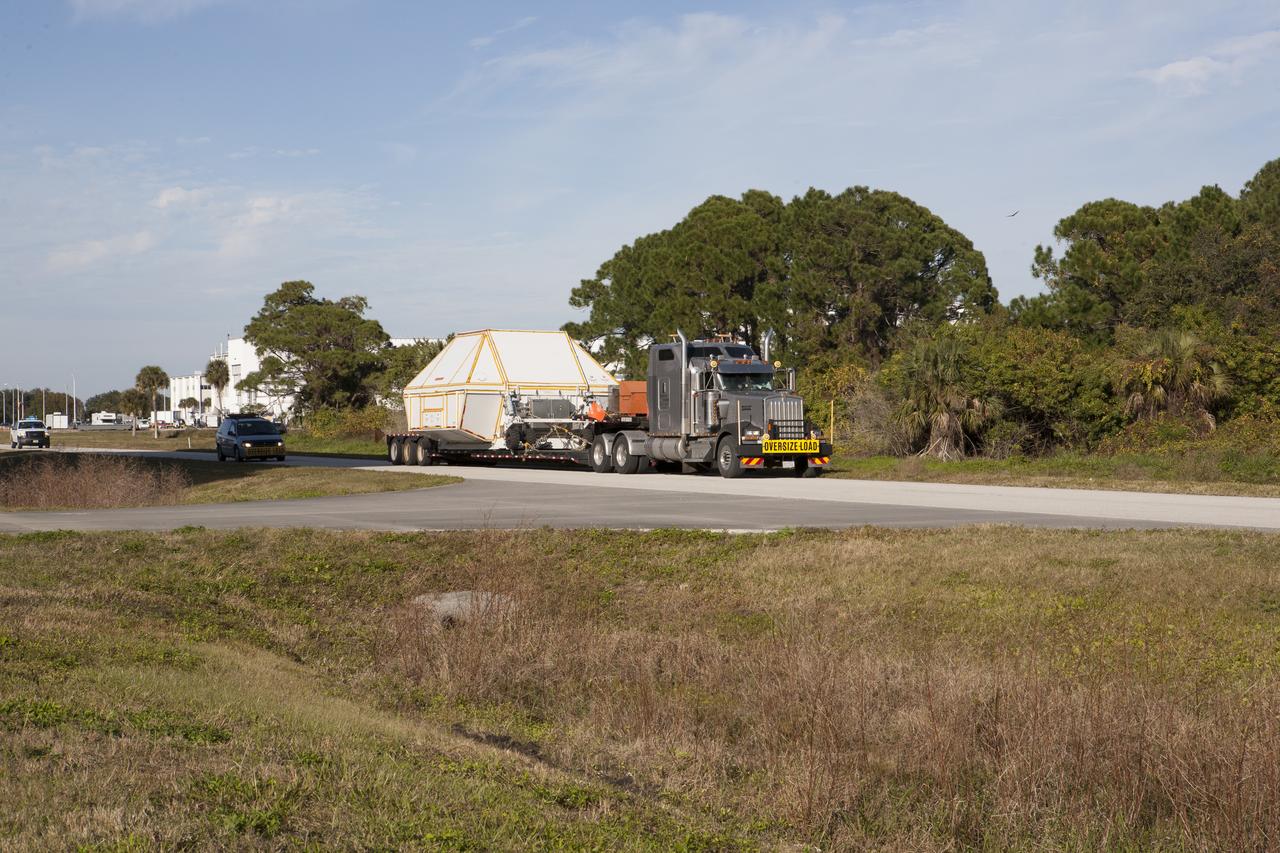 NASA's Orion crew module, enclosed in its crew module transportation fixture and secured on a flatbed truck, leaves the Multi-Operation Support Building and is being transported to the Launch Abort System Facility at NASA's Kennedy Space Center in Florida. Orion was transported 2,700 miles overland from Naval Base San Diego in California. Orion was recovered from the Pacific Ocean after completing a two-orbit, four-and-a-half hour mission Dec. 5 to test systems critical to crew safety, including the launch abort system, the heat shield and the parachute system. The Ground Systems Development and Operations Program led the recovery, offload and transportation efforts.