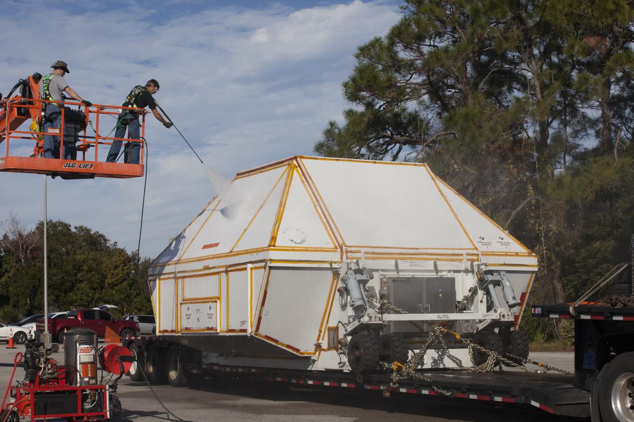 Technicians wash down the crew module transportation fixture containing the Orion crew module on the back of a flatbed truck at the Multi-Operation Support Building at NASA's Kennedy Space Center in Florida. Orion was transported 2,700 miles overland from Naval Base San Diego in California. Orion was recovered from the Pacific Ocean after completing a two-orbit, four-and-a-half hour mission Dec. 5 to test systems critical to crew safety, including the launch abort system, the heat shield and the parachute system. The Ground Systems Development and Operations Program led the recovery, offload and transportation efforts.
