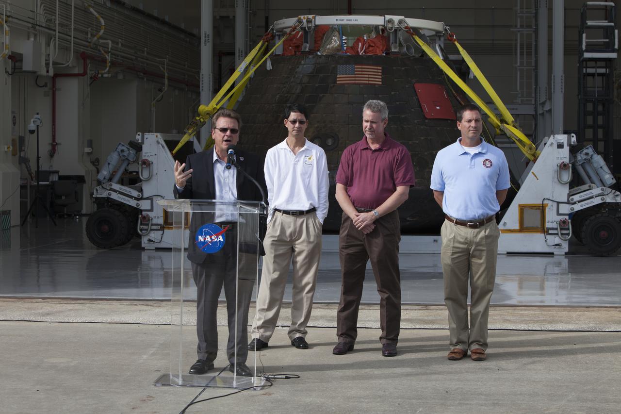 NASA's Orion spacecraft is viewed by members of the media at the Launch Abort System Facility at NASA's Kennedy Space Center in Florida. Speaking to the media during the viewing opportunity is Jules Schneider, Lockheed Martin Manager. Behind him, from left, are Glenn Chin, Orion Production Operations manager and Phil Weber and Lou Garcia, with the Ground Systems Development and Operations Program, or GSDO. Orion made the 8-day, 2,700 mile overland trip back to Kennedy from Naval Base San Diego in California. Analysis of date obtained during its two-orbit, four-and-a-half hour mission Dec. 5 will provide engineers with detailed information on how the spacecraft fared. GSDO led the recovery, offload and transportation efforts.