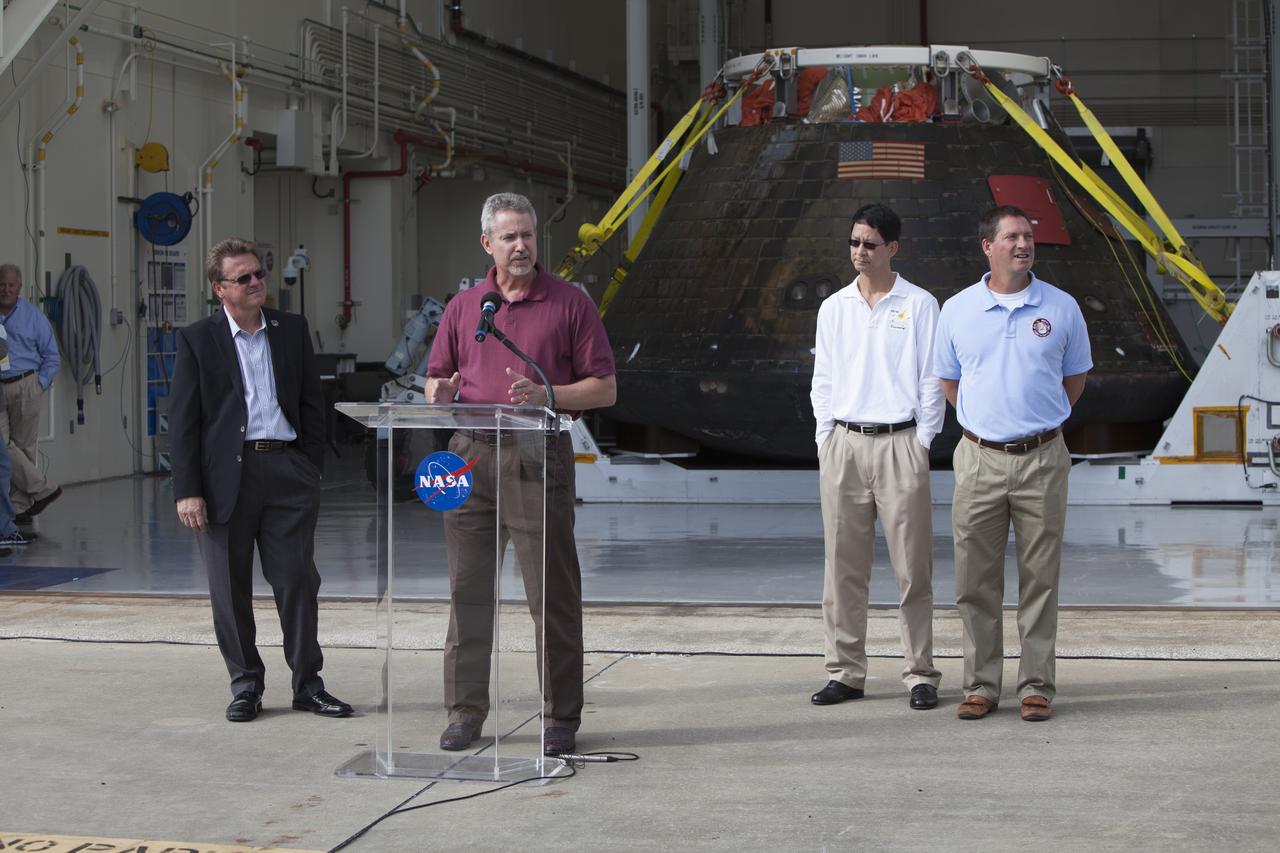 NASA's Orion spacecraft is viewed by members of the media at the Launch Abort System Facility at NASA's Kennedy Space Center in Florida. Speaking to the media during the viewing opportunity is Phil Weber, with the Ground Systems Development and Operations Program, or GSDO. At left is Jules Schneider, Lockheed Martin manager. At right is Glenn Chin, Orion Production Operations, and Lou Garcia, with GSDO. Orion made the 8-day, 2,700 mile overland trip back to Kennedy from Naval Base San Diego in California. Analysis of date obtained during its two-orbit, four-and-a-half hour mission Dec. 5 will provide engineers detailed information on how the spacecraft fared. GSDO led the recovery, offload and transportation efforts.