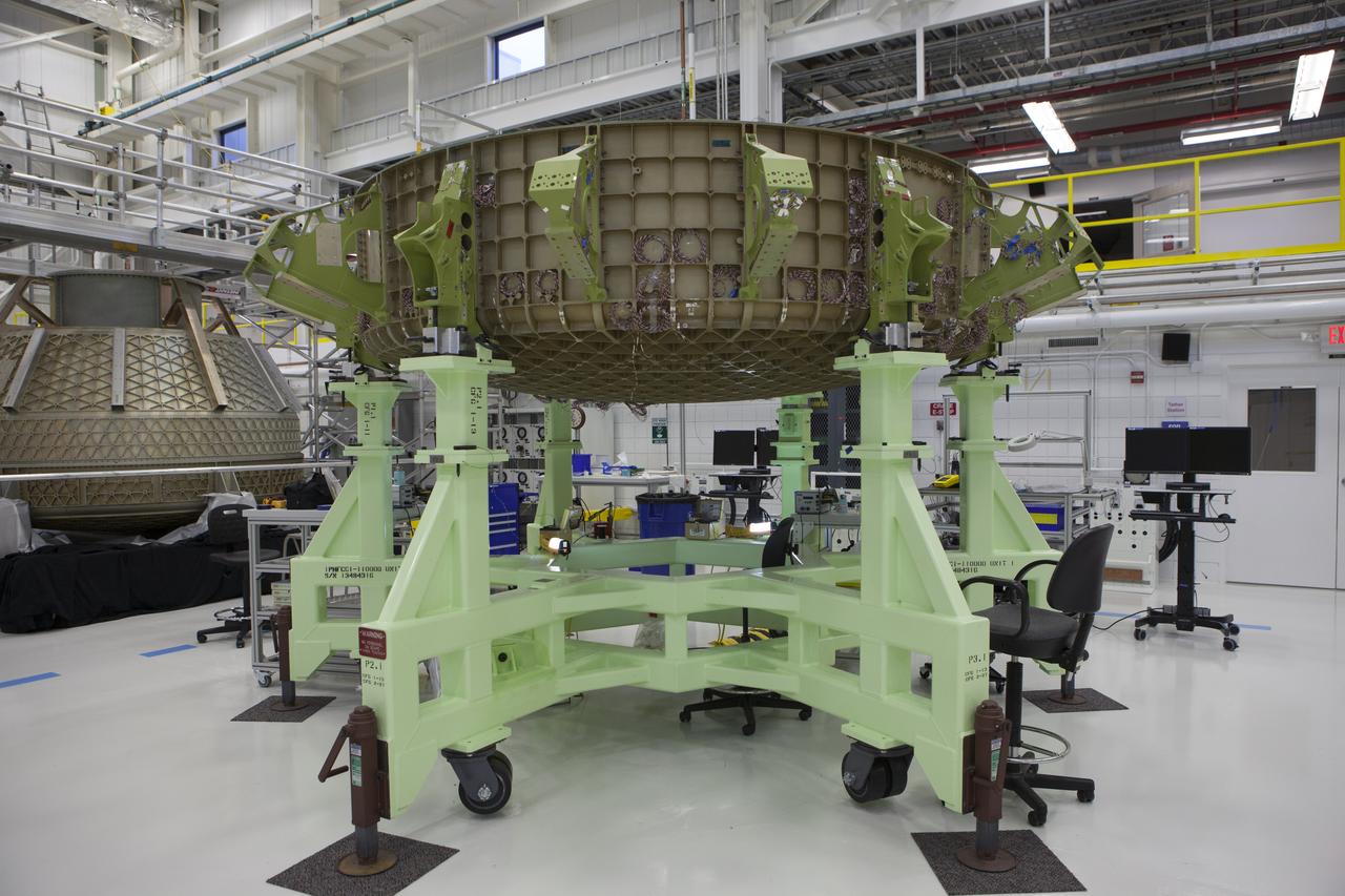 In the foreground, the lower dome of the Boeing CST-100 Structural Test Article rests on a test stand inside the Commercial Crew and Cargo Processing Facility, or C3PF, at NASA’s Kennedy Space Center in Florida. The test article will serve as a pathfinder for assembling and processing operational CST-100 spacecraft inside the revitalized facility, which for 20 years served as a shuttle processing hangar.
