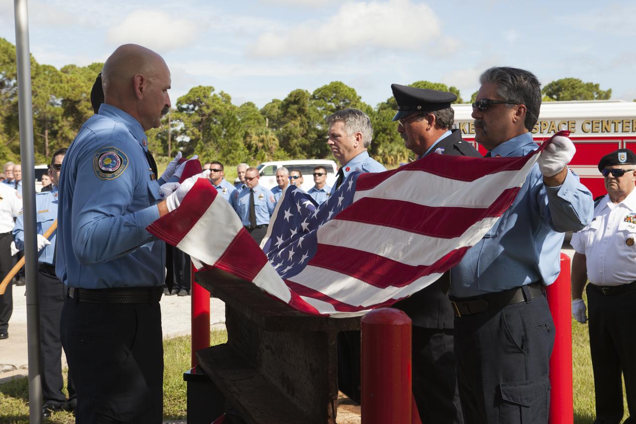An honor guard folds an American flag during the dedication service for a memorial to the 343 first responder victims of the Sept. 11, 2001, terror attacks at Fire Station 1 at NASA's Kennedy Space Center on Sept. 11, 2015. The ceremony dedicated a monument that includes a section of steel I-beam from the World Trade Center in New York. 