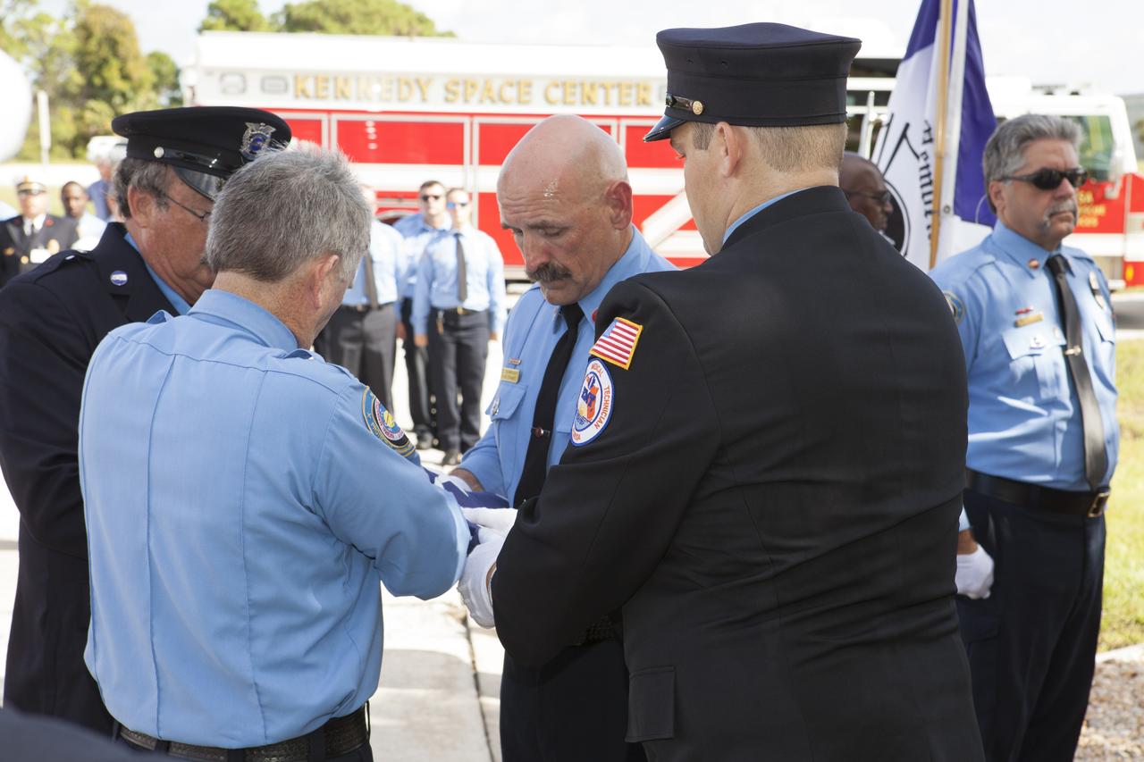An honor guard folds an American flag during the dedication service for a memorial to the 343 first responder victims of the Sept. 11, 2001, terror attacks at Fire Station 1 at NASA's Kennedy Space Center on Sept. 11, 2015. The ceremony dedicated a monument that includes a section of steel I-beam from the World Trade Center in New York.