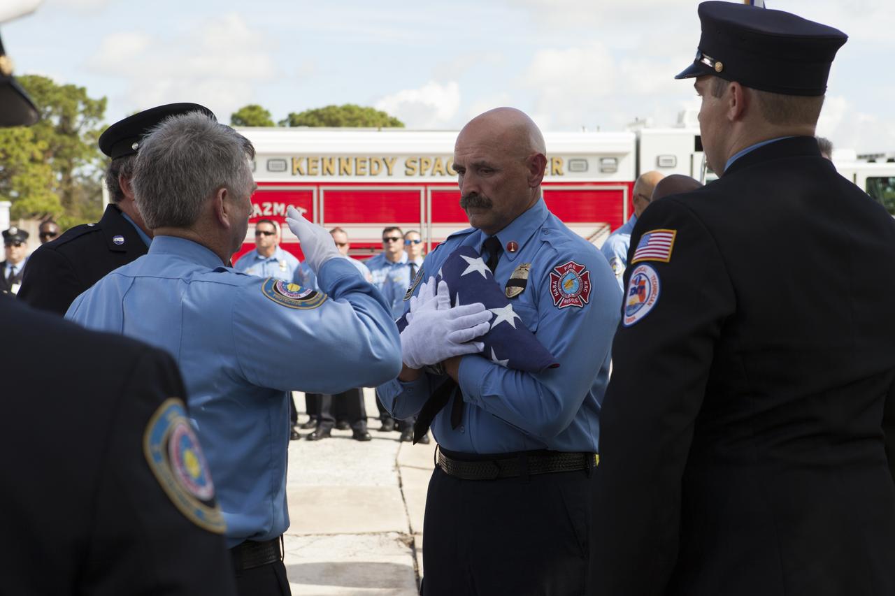 An honor guard folds an American flag during the dedication service for a memorial to the 343 first responder victims of the Sept. 11, 2001, terror attacks at Fire Station 1 at NASA's Kennedy Space Center on Sept. 11, 2015. The ceremony dedicated a monument that includes a section of steel I-beam from the World Trade Center in New York.