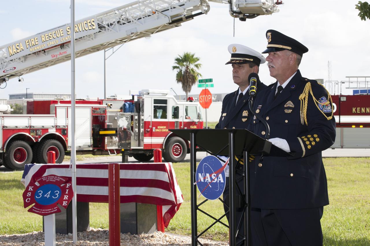 Rick Anderson, fire chief at NASA's Kennedy Space Center, on podium, left, and Lt. James Dumont lead the dedication service for a memorial to the 343 first responder victims of the Sept. 11, 2001, terror attacks at Kennedy's Fire Station 1 on Sept. 11, 2015. The ceremony dedicated a monument that includes a section of steel I-beam from the World Trade Center in New York.