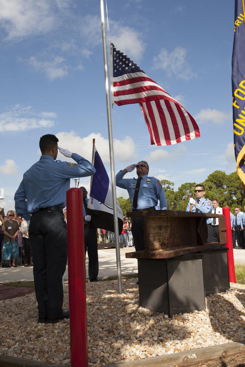 Firefighters place the American flag at half-staff during dedication services for a memorial to the 343 first responder victims of the Sept. 11, 2001, terror attacks at Fire Station 1 at NASA's Kennedy Space Center on Sept. 11, 2015. A section of steel I-beam from the World Trade Center in New York forms the centerpiece of the monument.