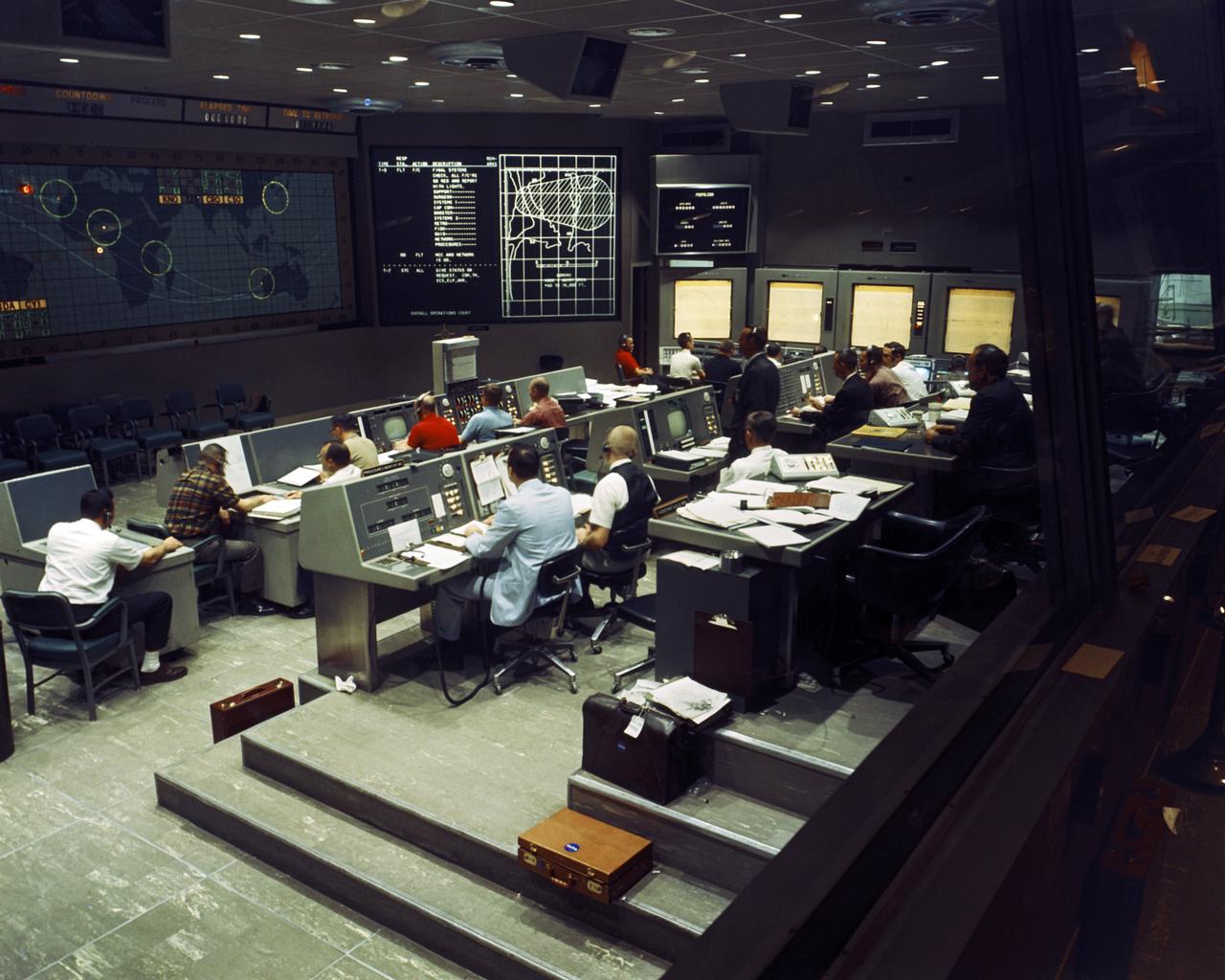 CAPE CANAVERAL, Fla. - Inside the Mission Control Center, flight controllers work during the Gemini I mission, an orbital test of the Titan-II launch vehicle.    The Mercury Mission Control Center in Florida played a key role in the United States' early spaceflight program. Located at Cape Canaveral Air Force Station, the original part of the building was constructed between 1956 and 1958, with additions in 1959 and 1963. The facility officially was transferred to NASA on Dec. 26, 1963, and served as mission control during all the Project Mercury missions, as well as the first three flights of the Gemini Program, when it was renamed Mission Control Center. With its operational days behind, on June 1, 1967, the Mission Control Center became a stop on the public tour of NASA facilities until the mid-90s. In 1999, much of the equipment and furnishings from the Flight Control Area were moved to the Kennedy Space Center Visitor Complex where they became part of the exhibit there. The building was demolished in spring 2010. Photo credit: NASA